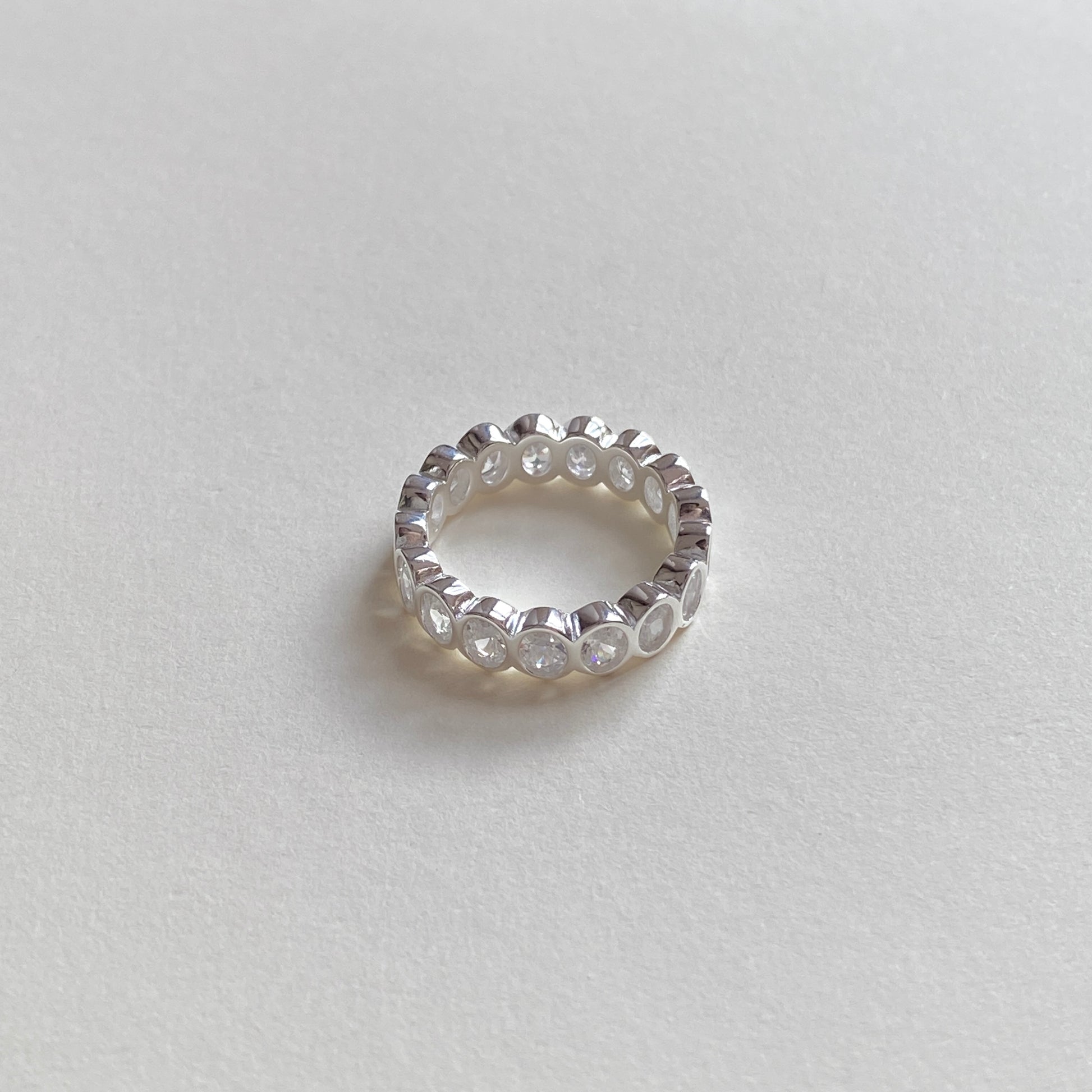Bezel-set oval cubic zirconia eternity ring angled to show continuous stones and comfort-fit shank in 925 sterling silver.