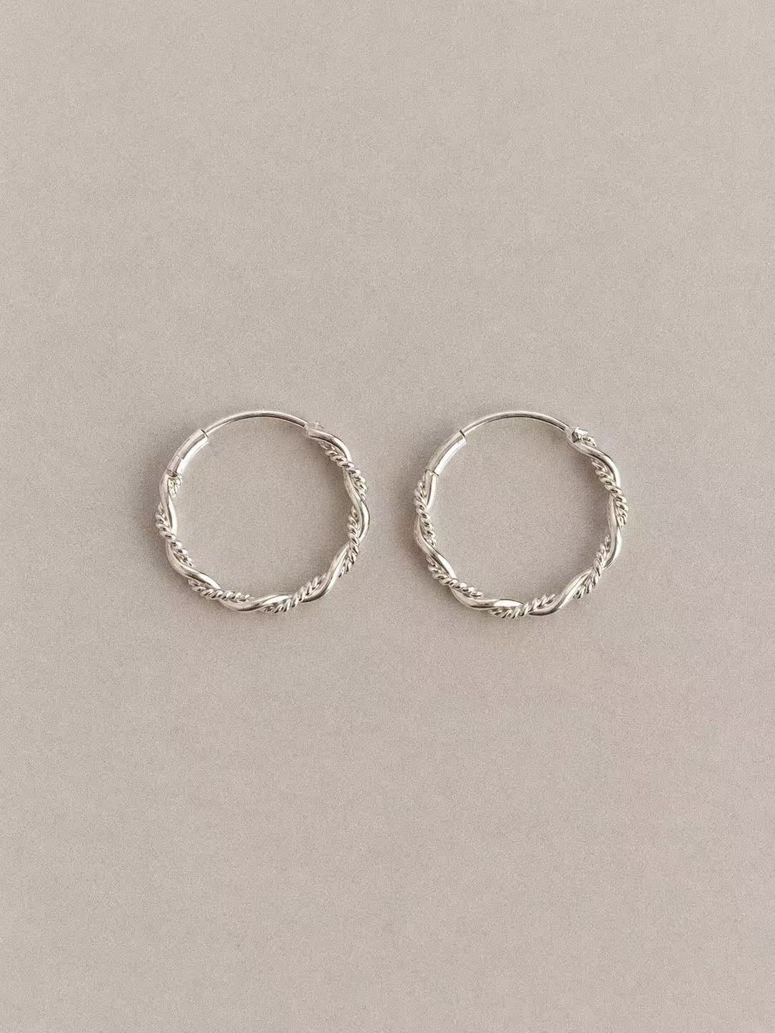 Pair of Mobius twisted hoop earrings in 925 sterling silver on a neutral background