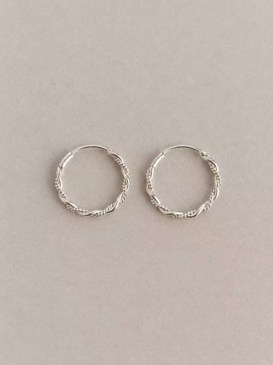Pair of Mobius twisted hoop earrings in 925 sterling silver on a neutral background