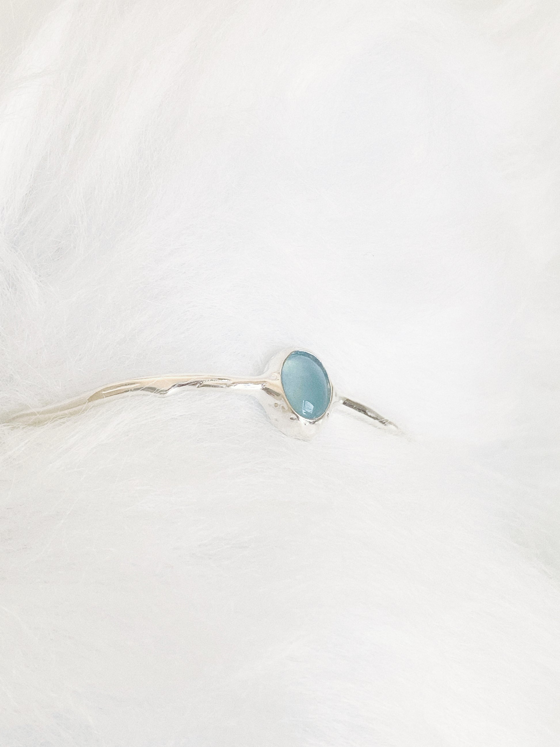 Close up of the natural aquamarine cabochon and textured silver bezel on a soft white background