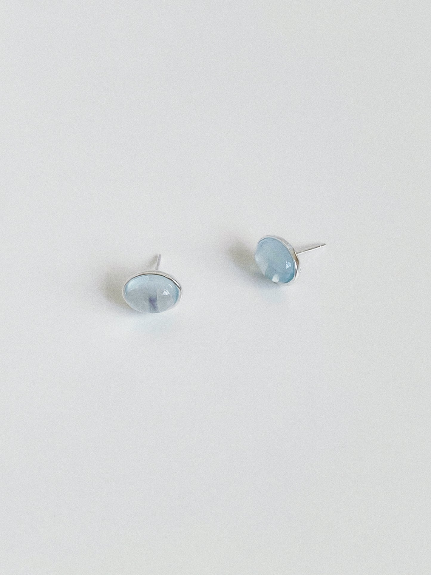 Angled view of natural aquamarine stud earrings showing the soft watery blue of the March birthstone cabochons