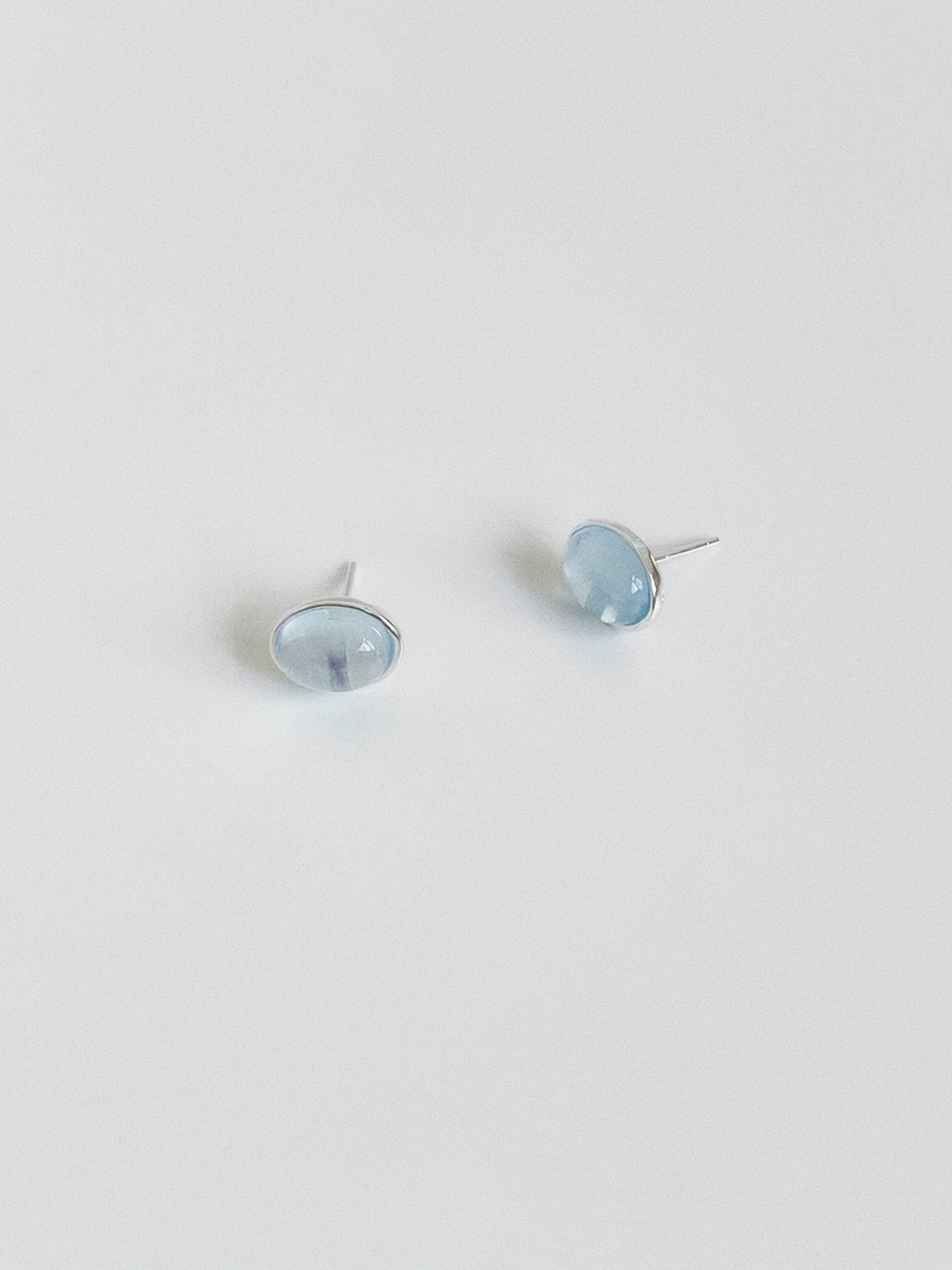 Angled view of natural aquamarine stud earrings showing the soft watery blue of the March birthstone cabochons
