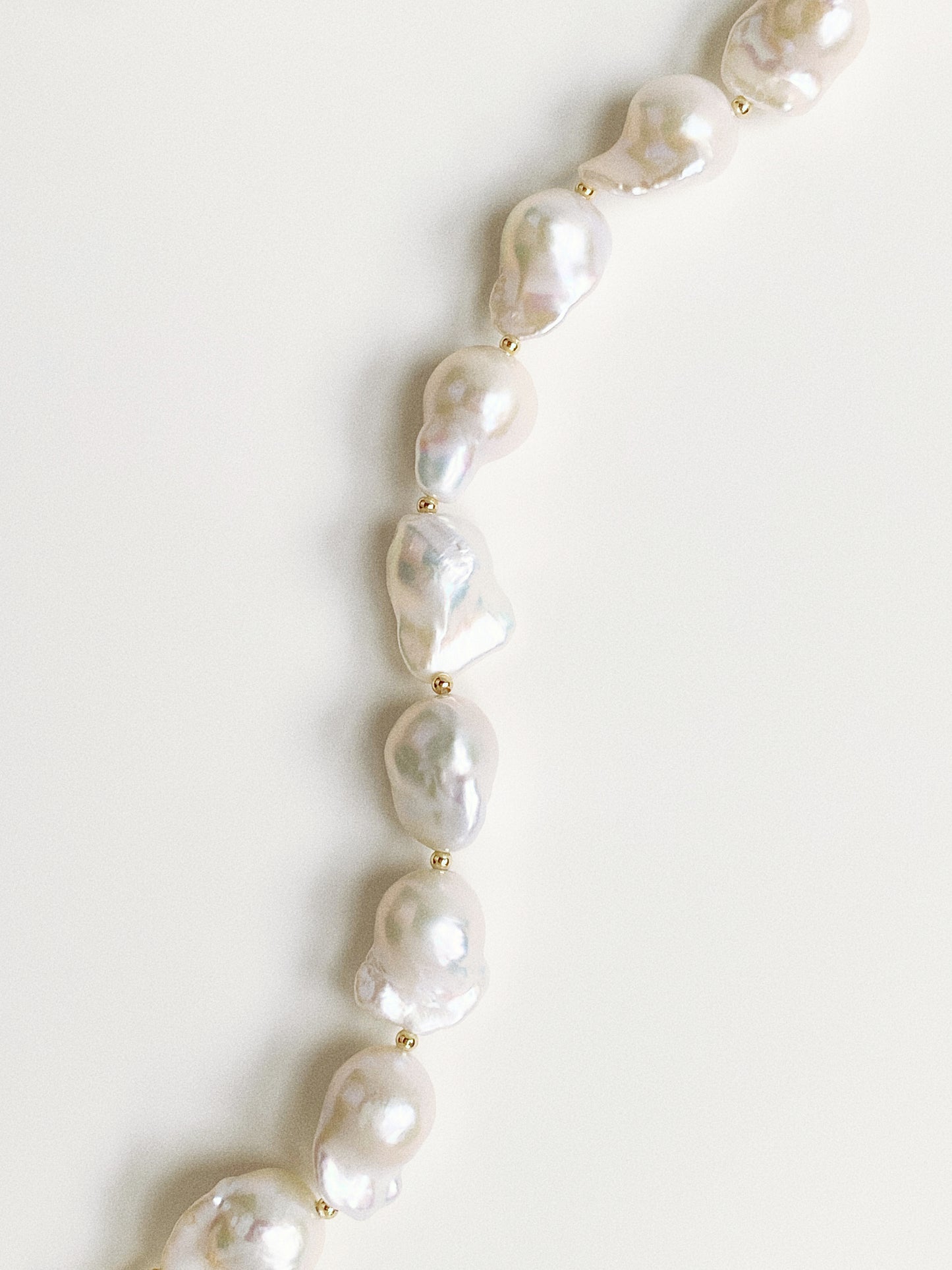 Macro detail shot of the natural ridges and high-gloss surface of the large baroque pearls.