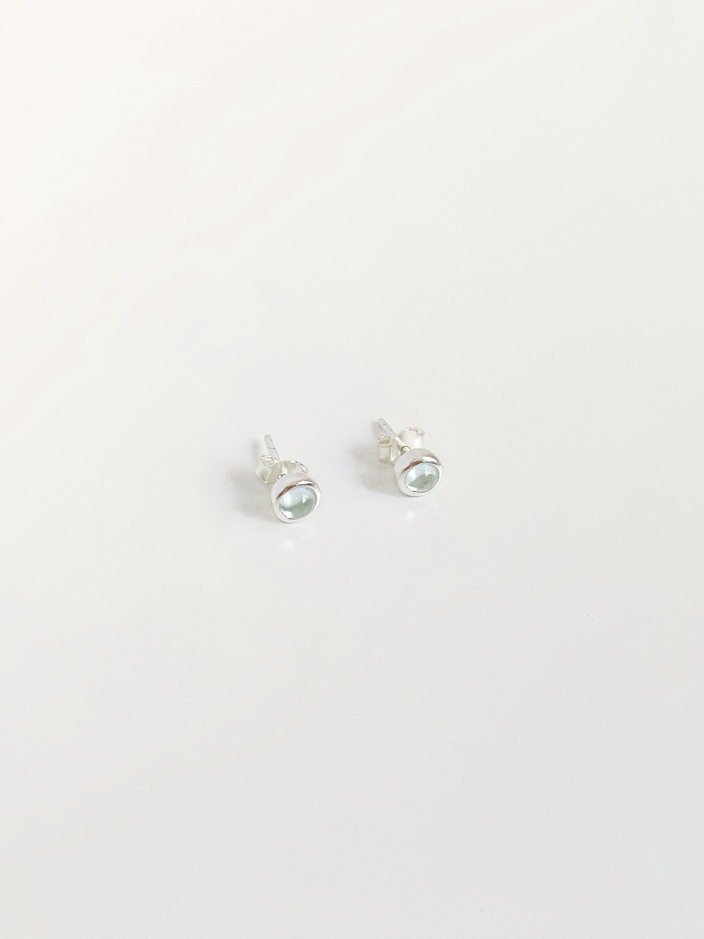 5-6mm natural blue topaz cabochon stud earrings showing soft glow and sterling silver bezel setting