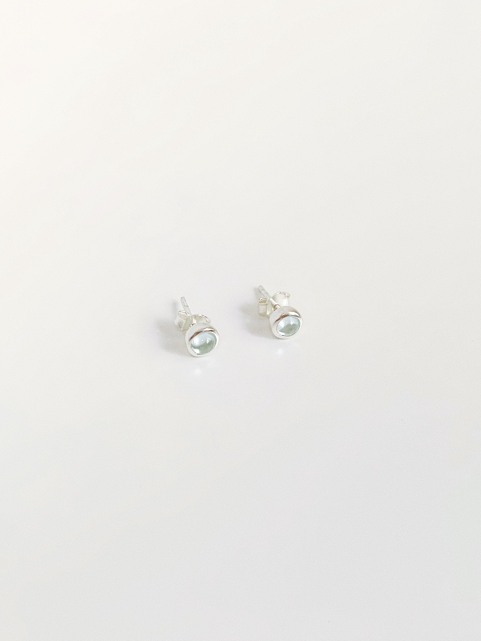 5-6mm natural blue topaz cabochon stud earrings showing soft glow and sterling silver bezel setting