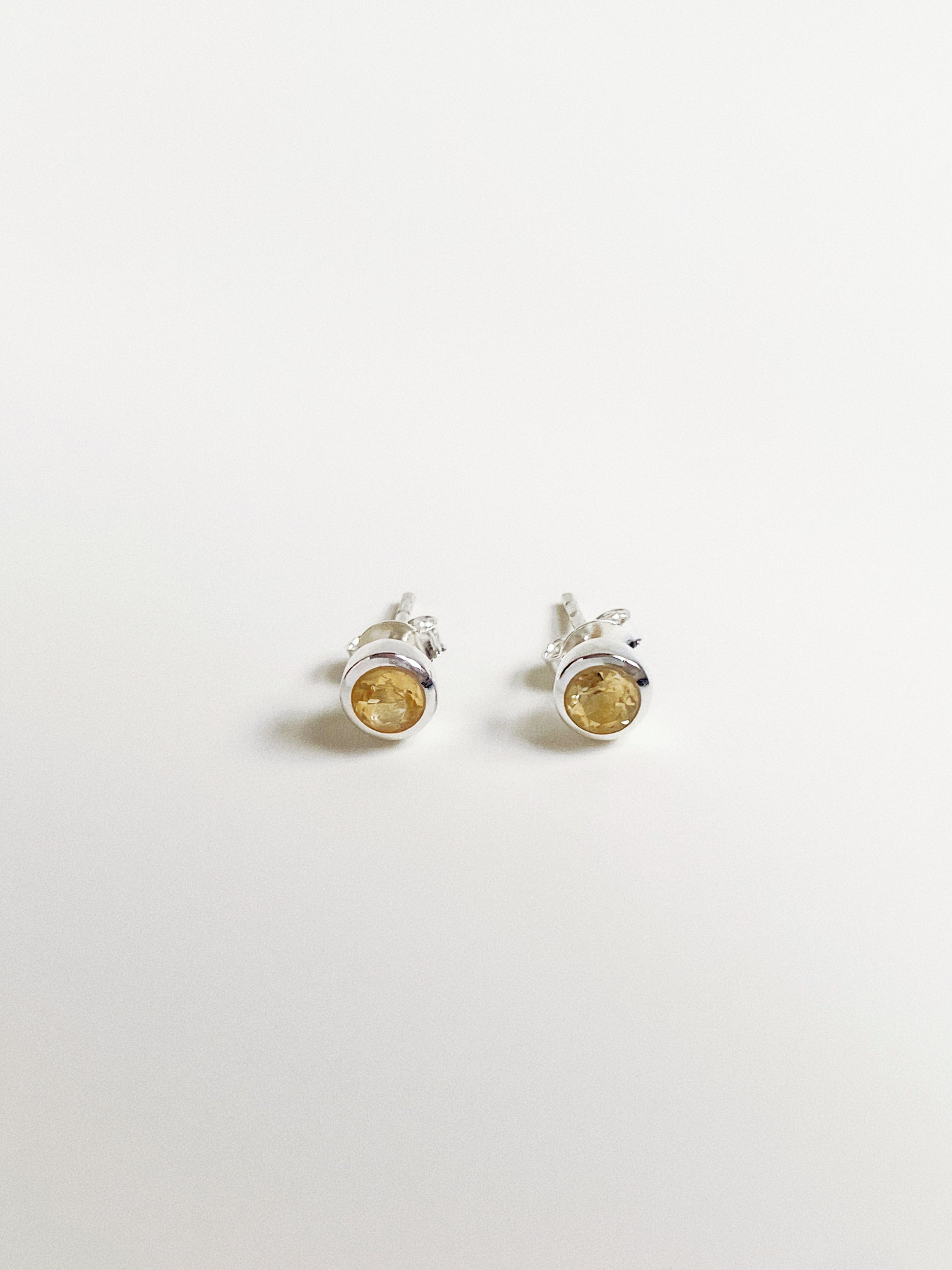 Front view of 5-6mm round faceted natural citrine stud earrings in sterling silver bubble bezel setting.