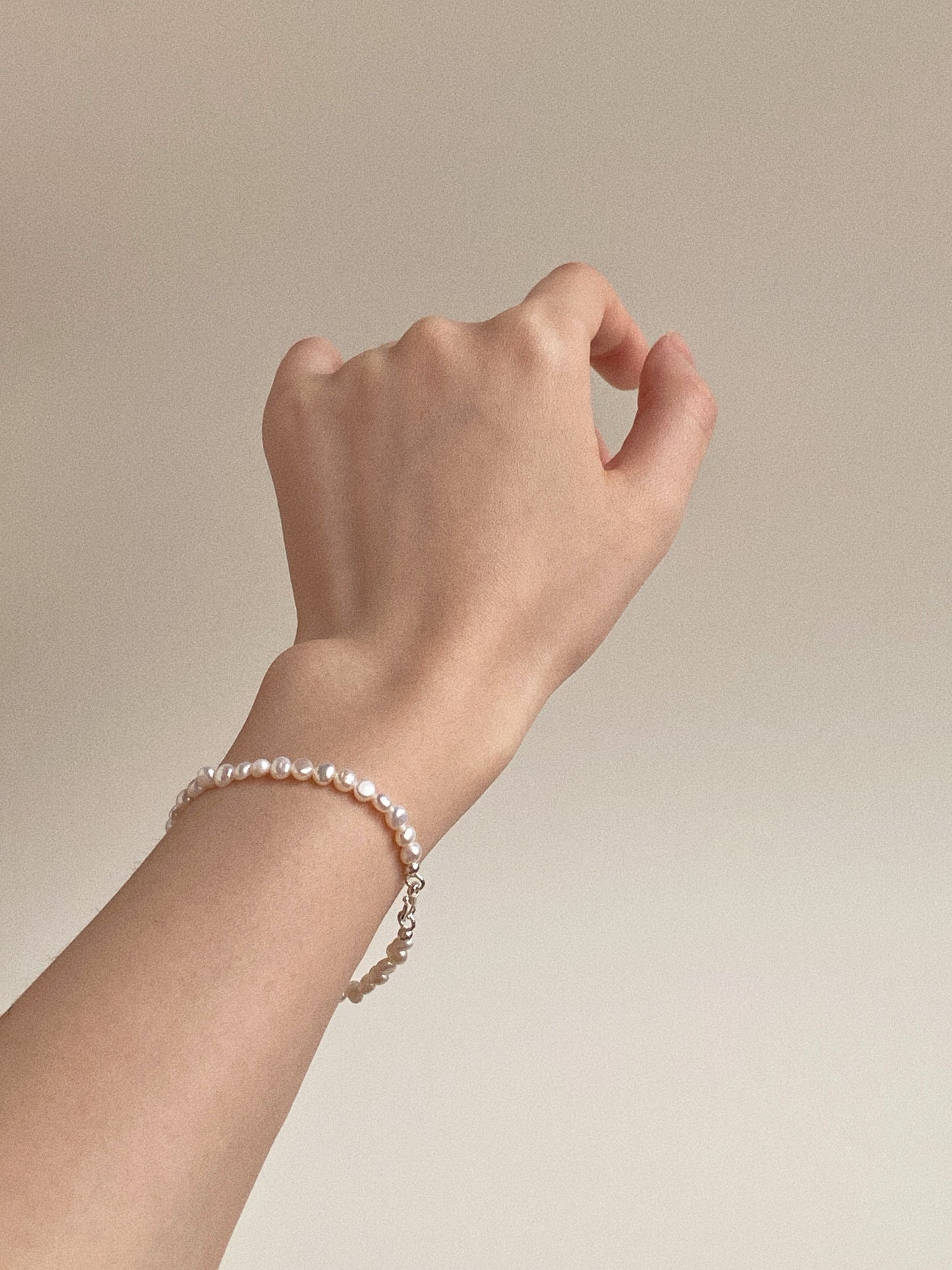 Aesthetic side profile shot of the mini pearl bracelet on a woman's wrist.