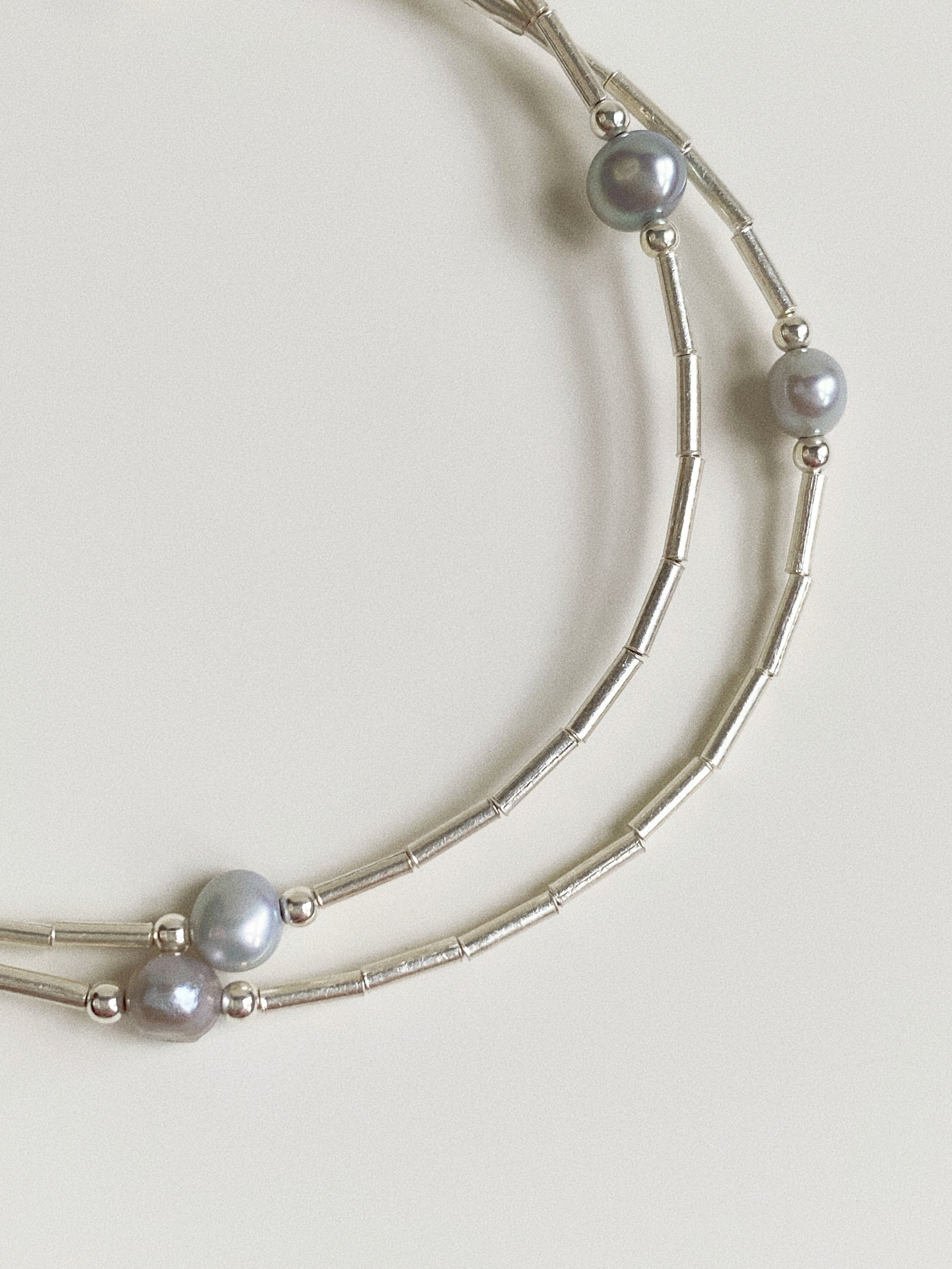 Close-up of natural grey freshwater pearls on liquid silver bar chain showing soft pearl lustre