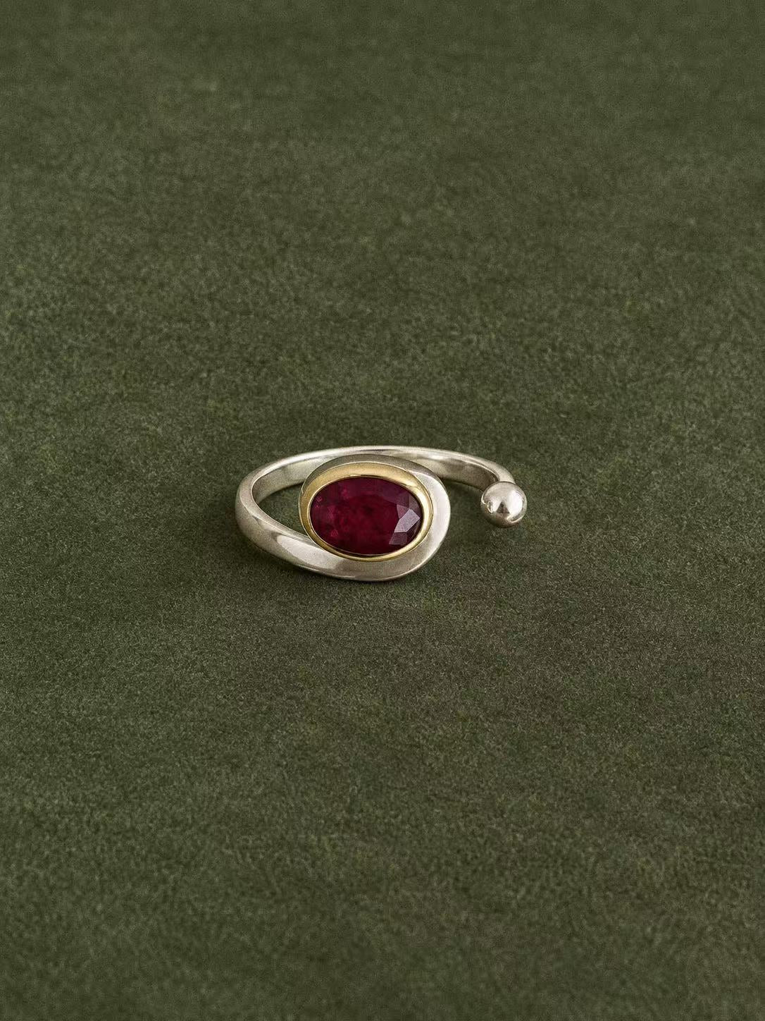 Front view of the oval natural ruby, brass bezel and rounded silver end on an open ring