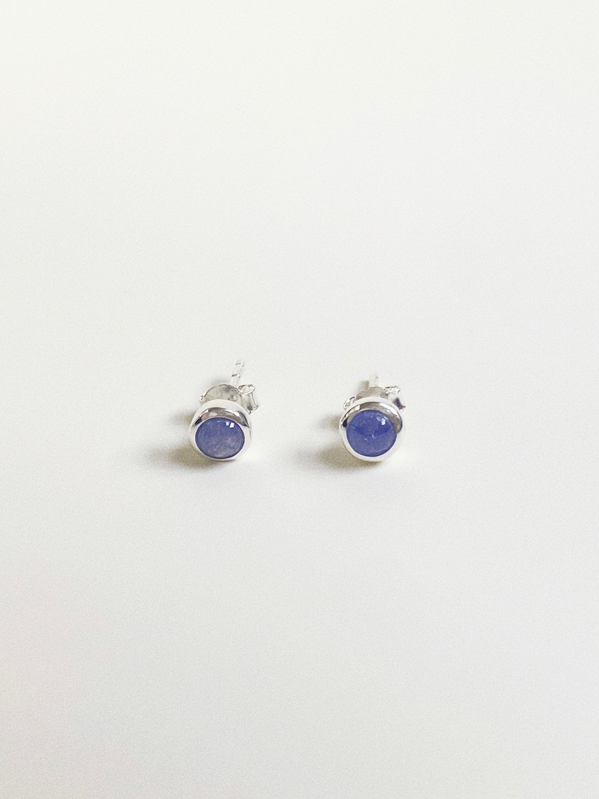 Pair of round 5-6mm natural Tanzanite cabochon stud earrings in sterling silver bezel setting.