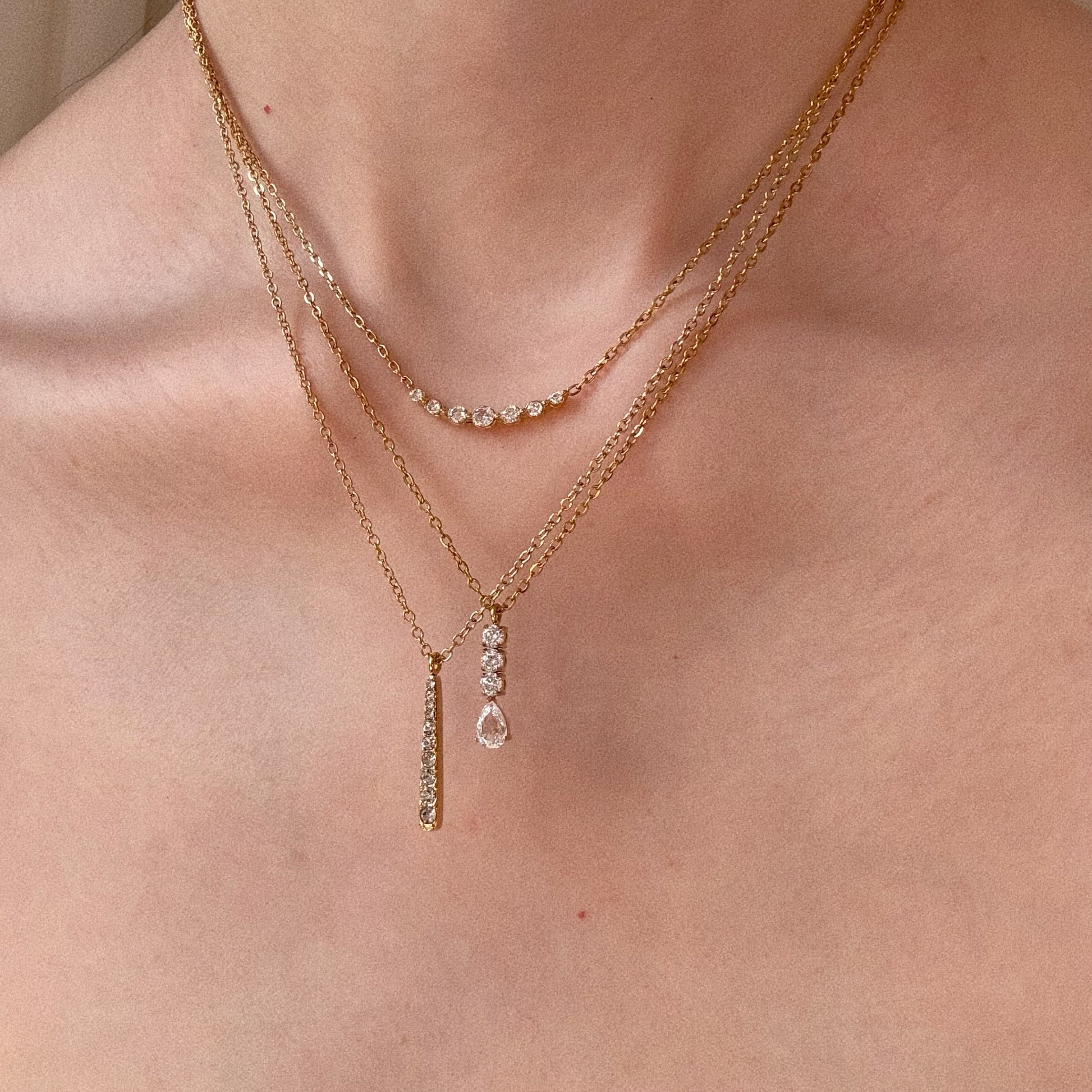 The ultimate gold necklace stack: Smile Bar (top), Teardrop (middle), and Nova Linear Bar (bottom) on model.