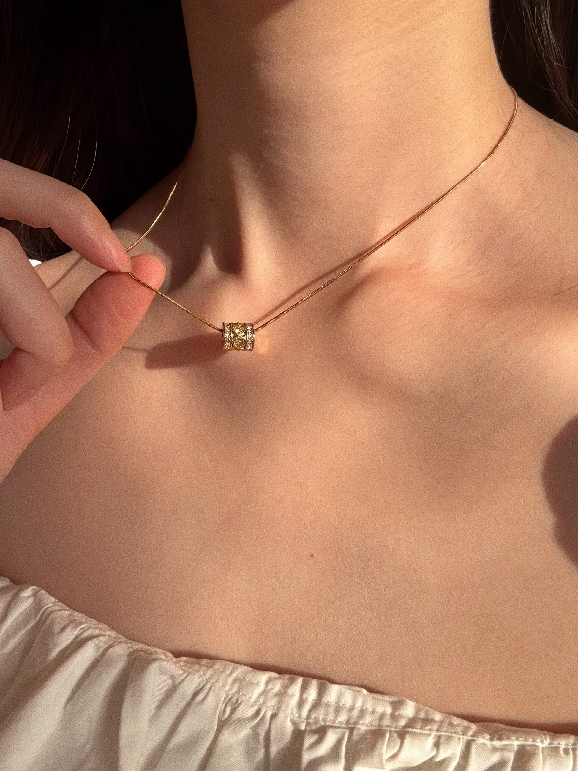 Woman holding the crystal heart barrel pendant, highlighting the intricate pave details and romantic design.