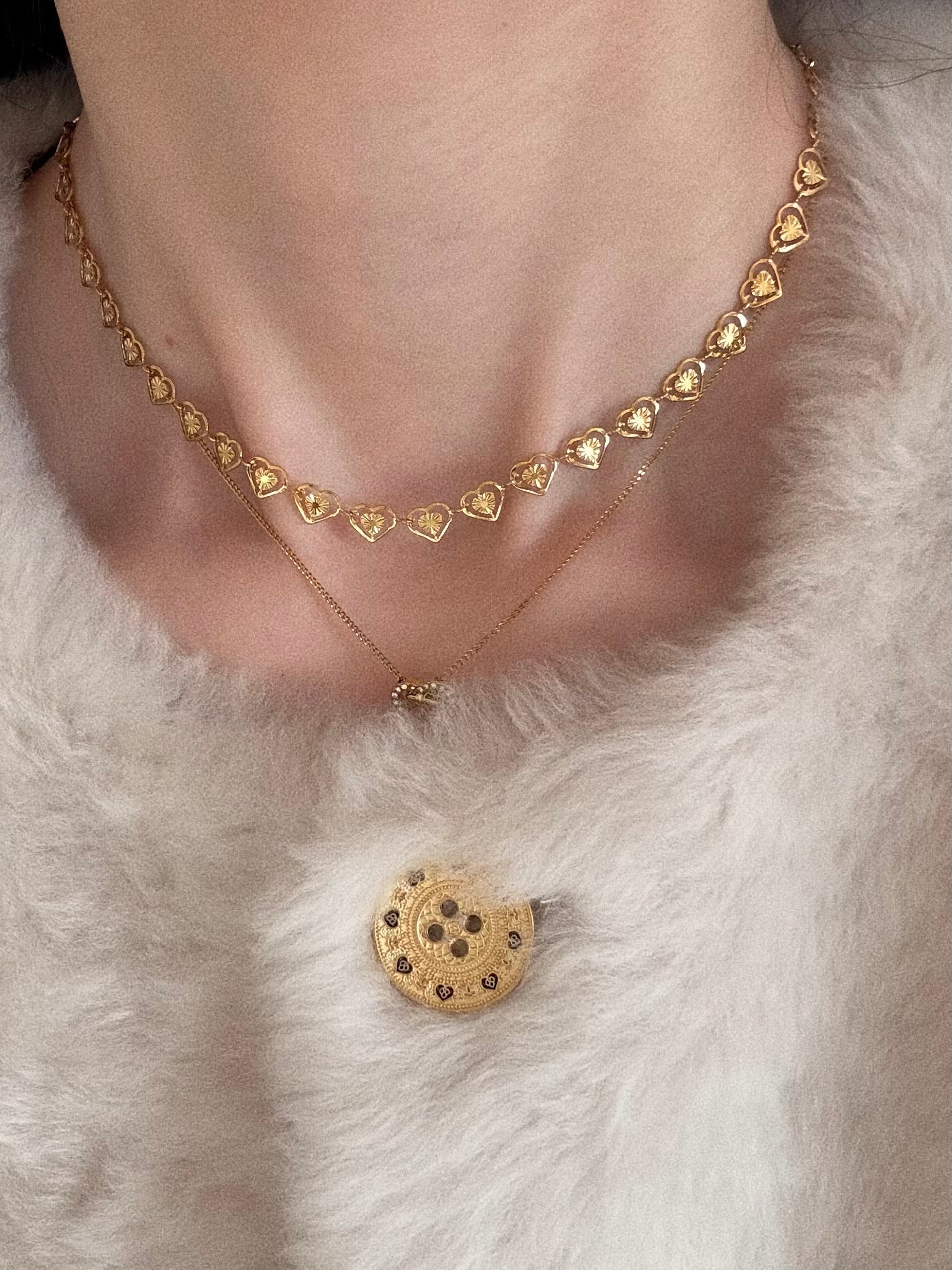 Model wearing the Amour Heart Choker layered with a pendant necklace, styled cozily with a white fuzzy cardigan.