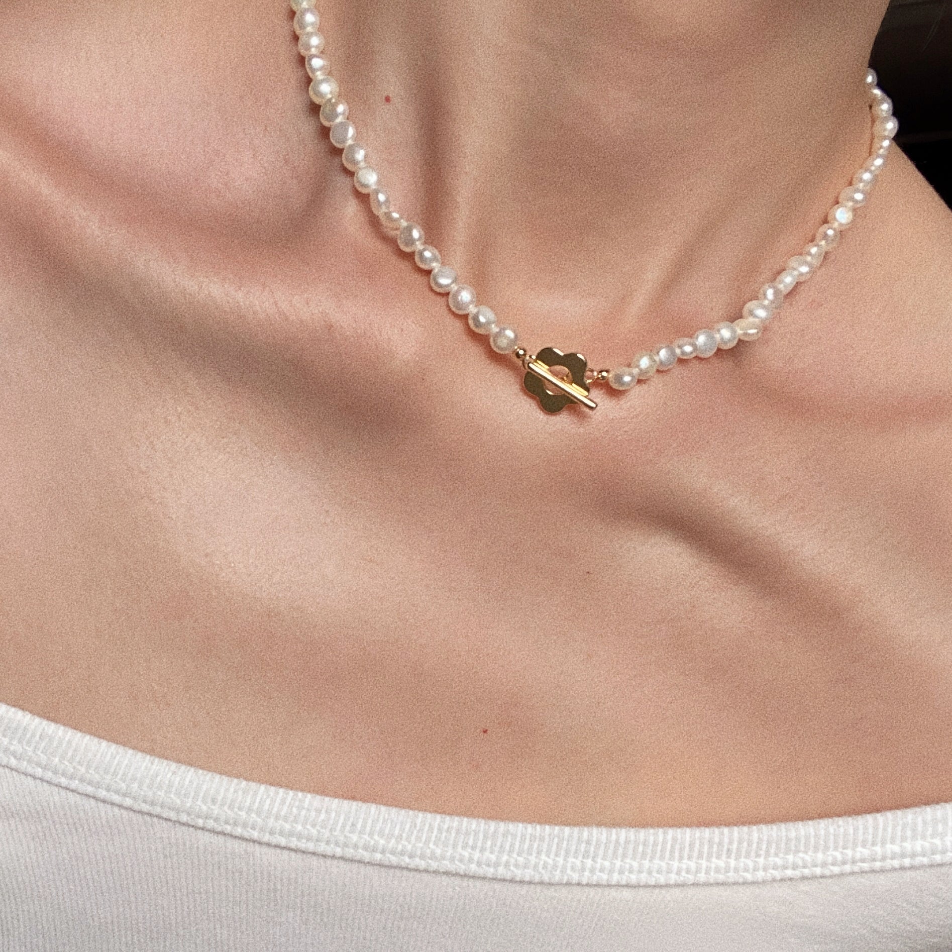 Close up of freshwater pearl necklace with front flower toggle clasp styled as dainty choker