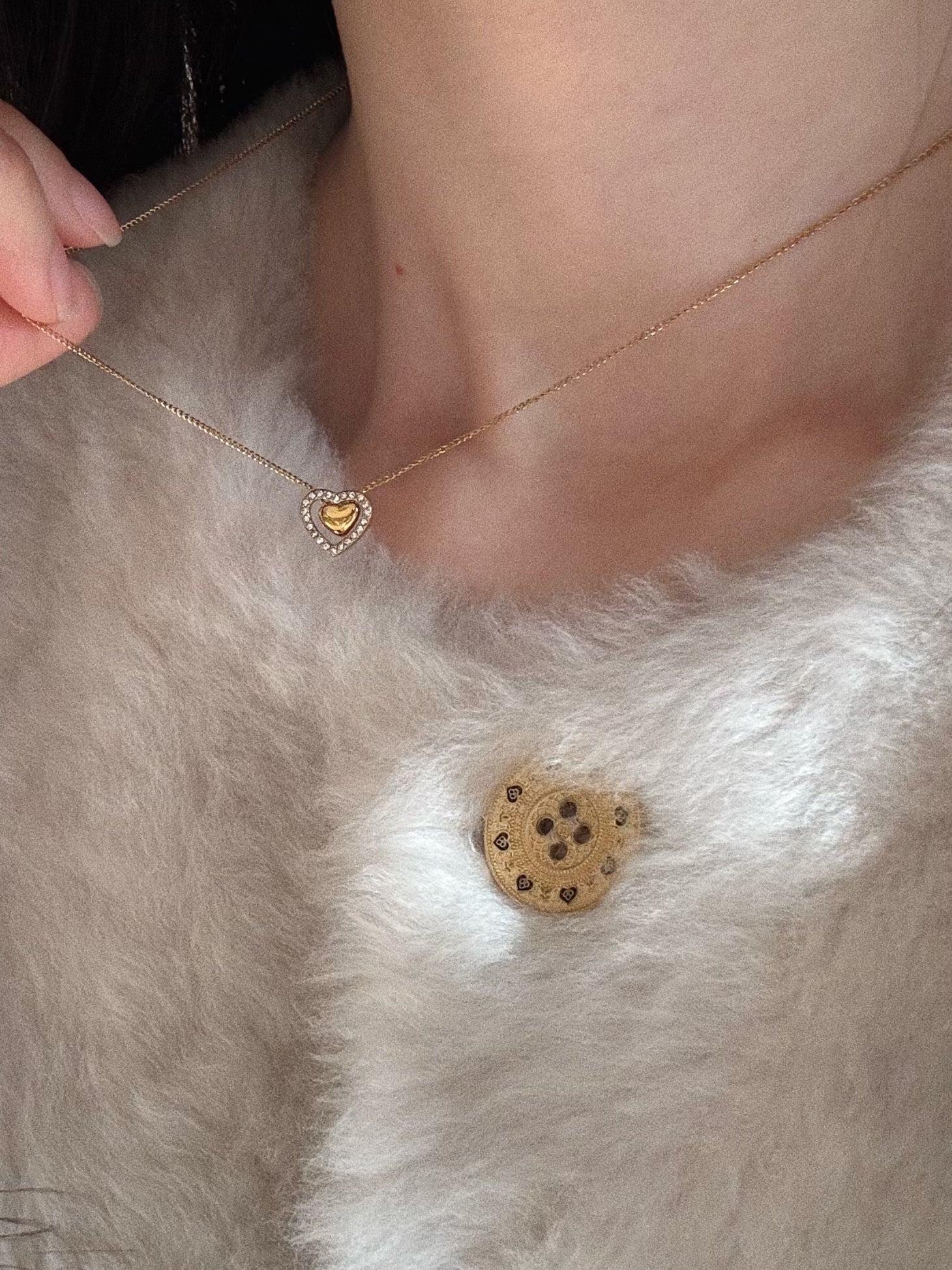 Styling shot of the waterproof gold heart necklace paired with a cozy cardigan, perfect Valentine's Day jewelry.