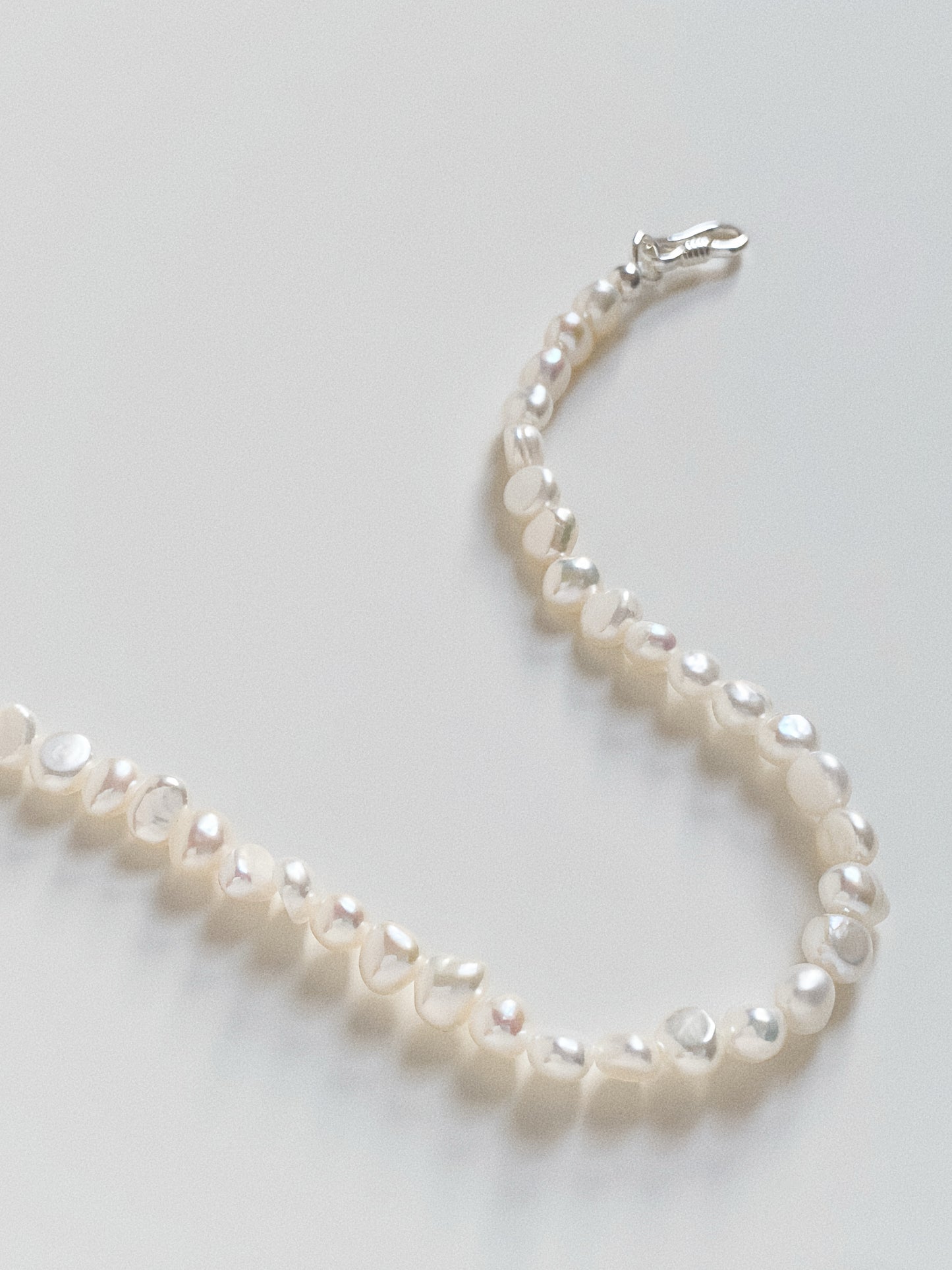 Macro shot of the 4-5mm baroque pearls arranged in a curve, showing their unique organic texture.