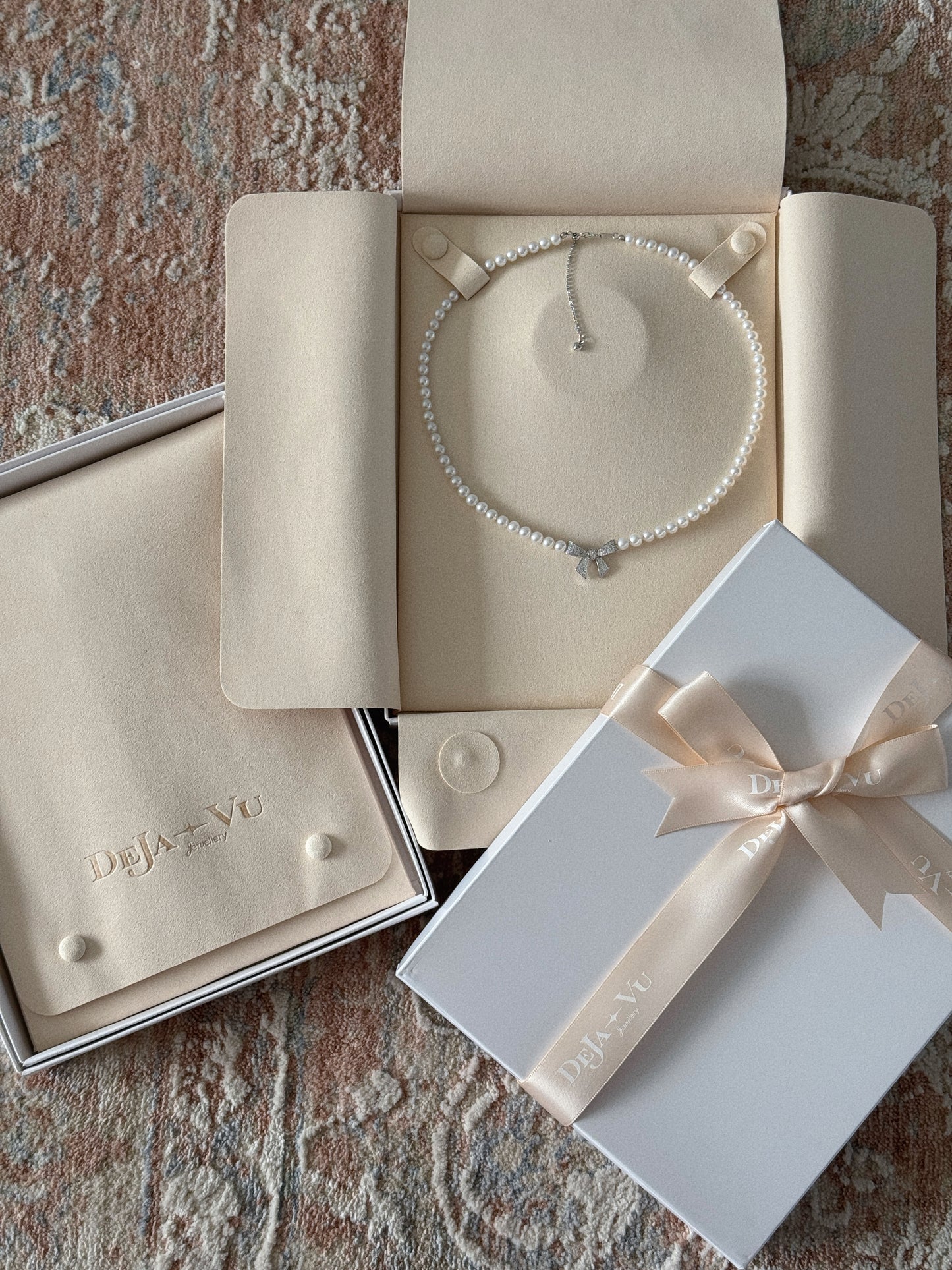 Pearl bow necklace displayed in a Deja Vu suede jewellery folder with white gift box and satin ribbon