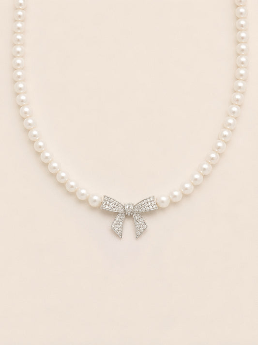 Pearl bow necklace with a full strand of white pearls and a pavé crystal bow sitting at the centre