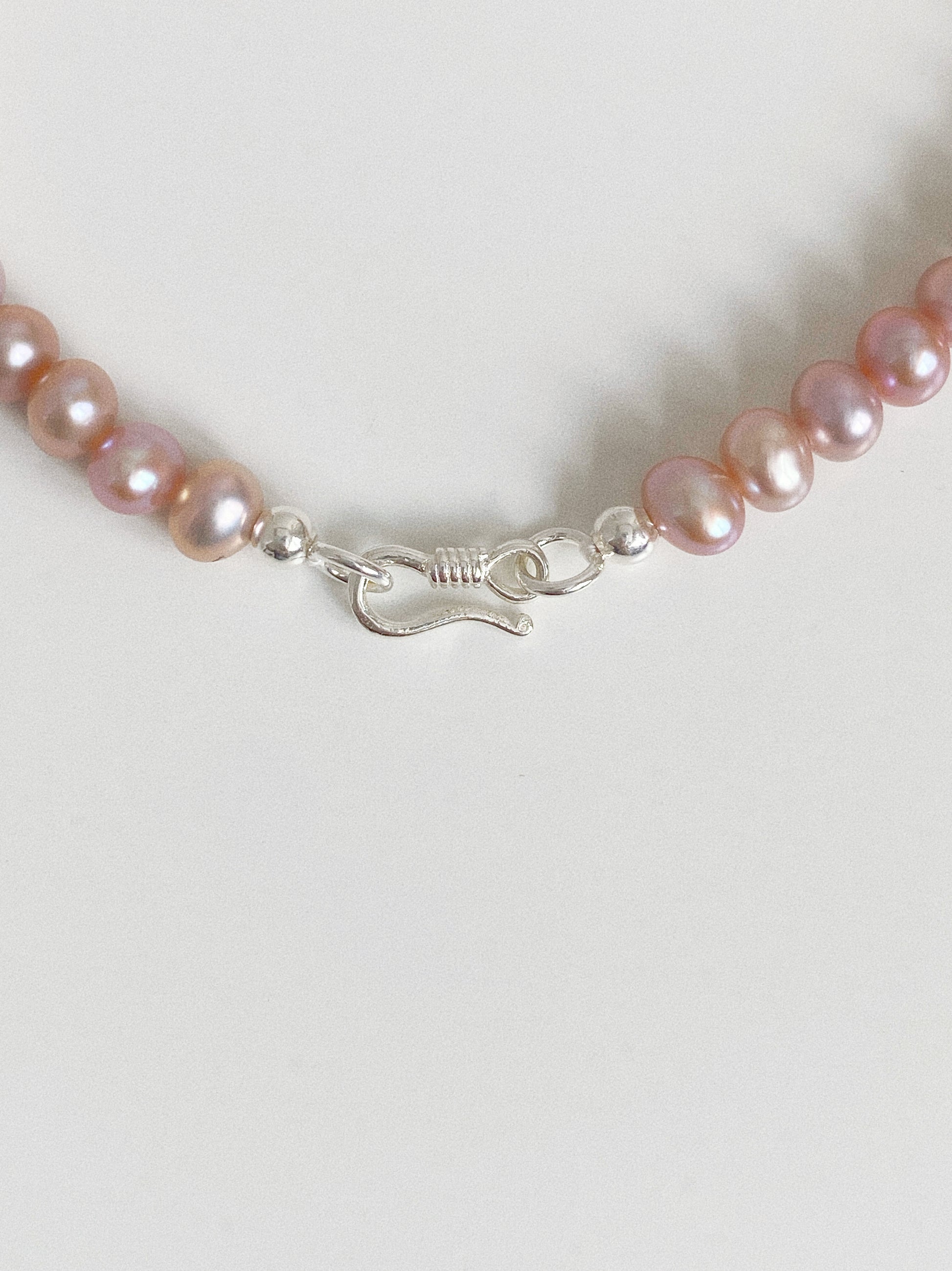 Close-up of the 925 sterling silver S-hook clasp and polished silver beads on a lavender freshwater pearl bracelet