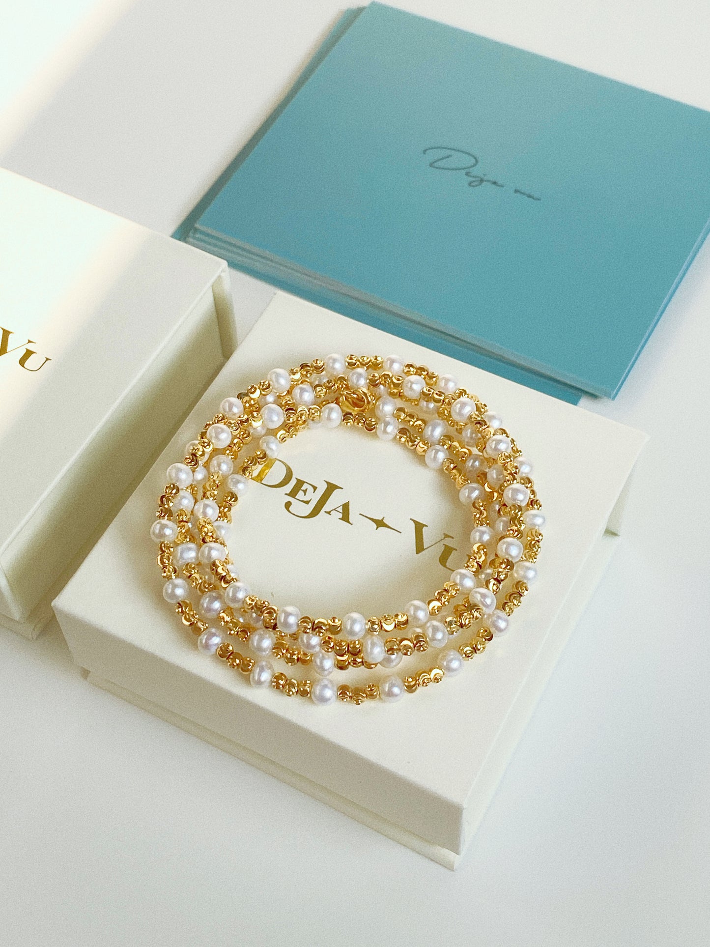 Long pearl and gold bead wrap necklace coiled inside Deja Vu Jewellery branded gift box