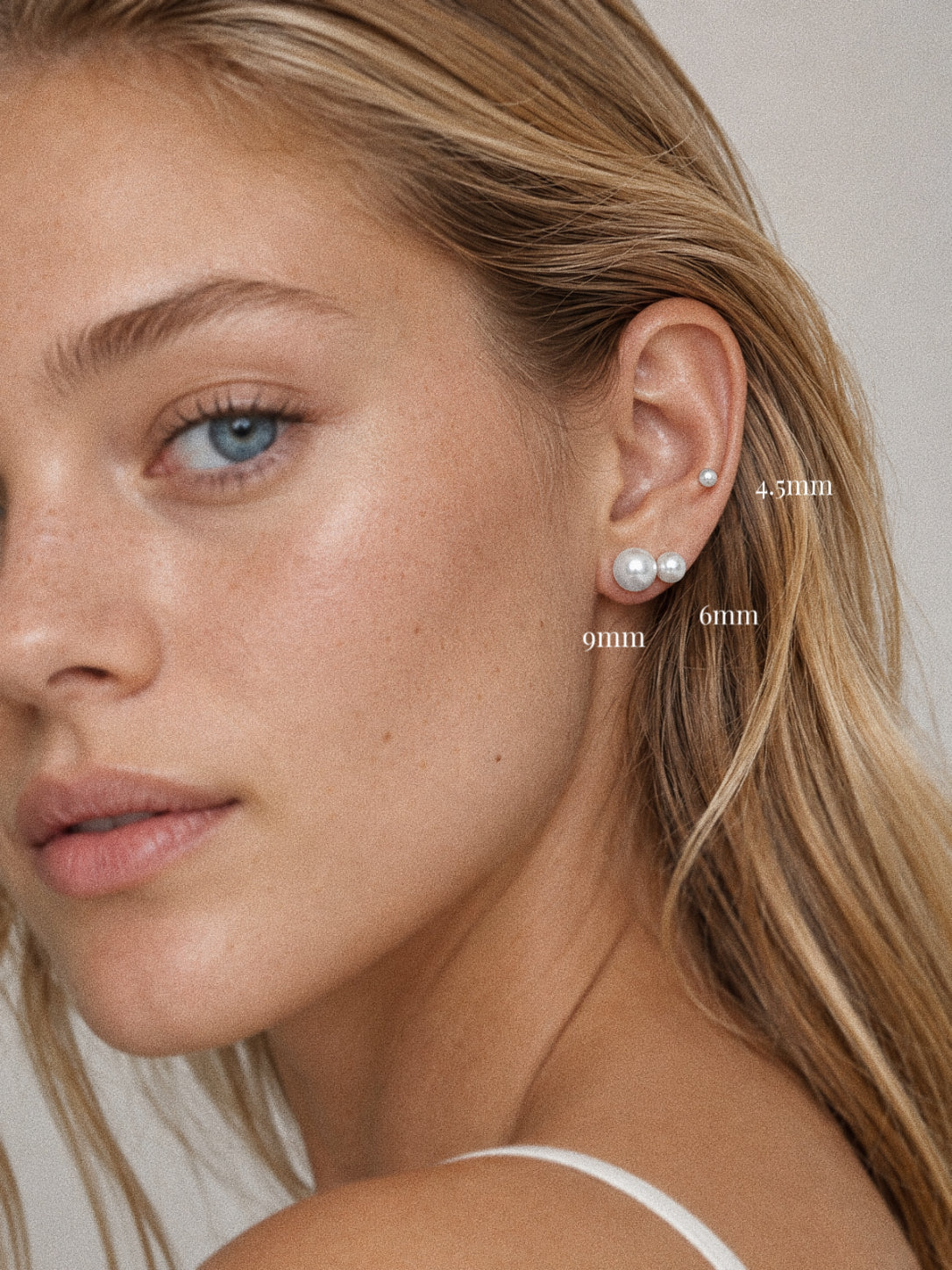 Pearl stud earrings worn on the ear in 4.5 mm, 6 mm and 9 mm, the largest pearl sitting at the lobe.