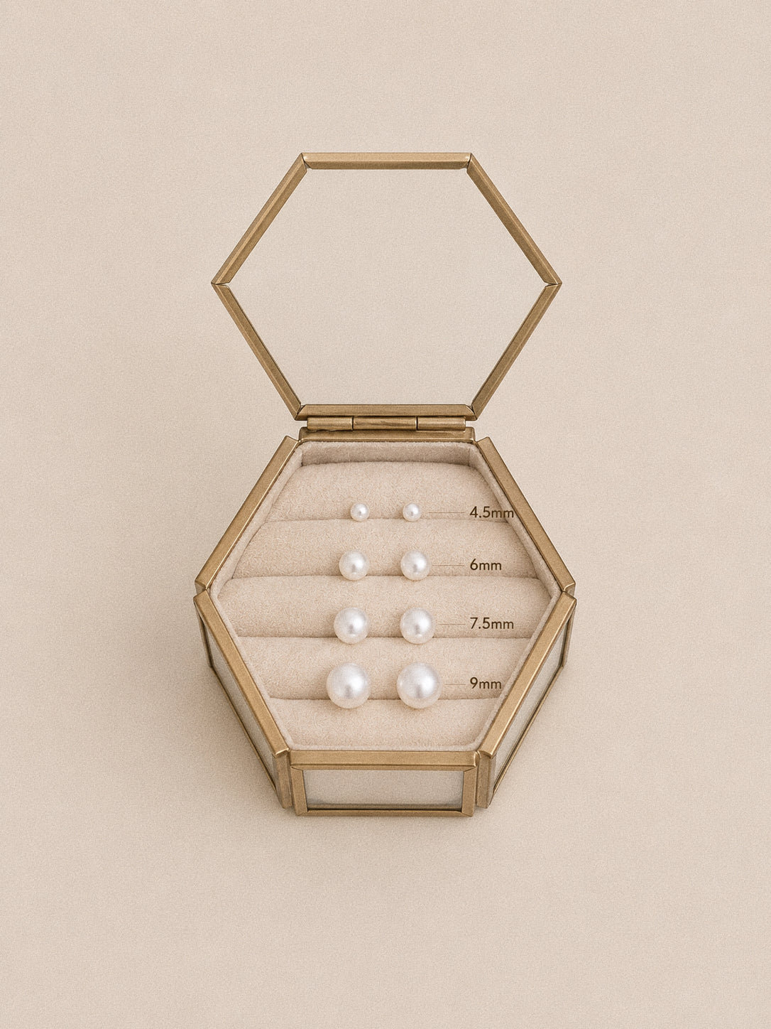 Pearl stud earrings in four sizes labelled 4.5 mm, 6 mm, 7.5 mm and 9 mm, arranged in a hexagonal glass box.