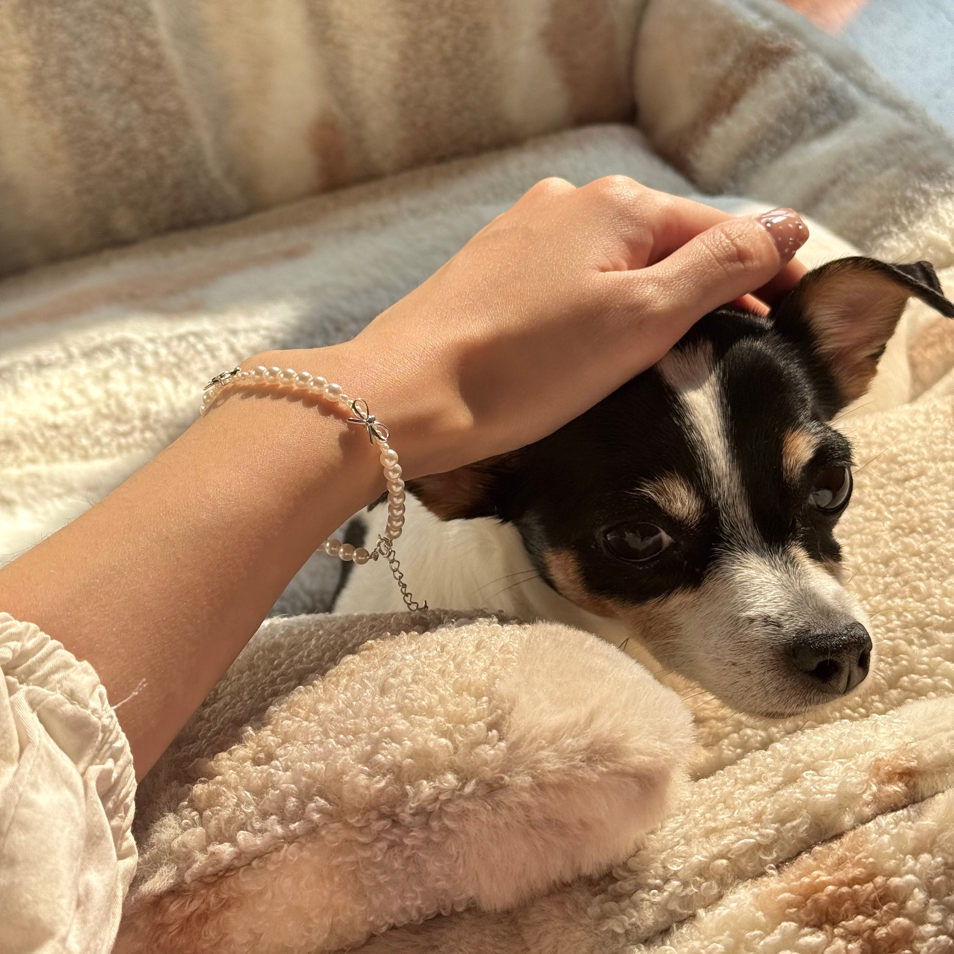 pearl bracelet with silver bow charms on wrist