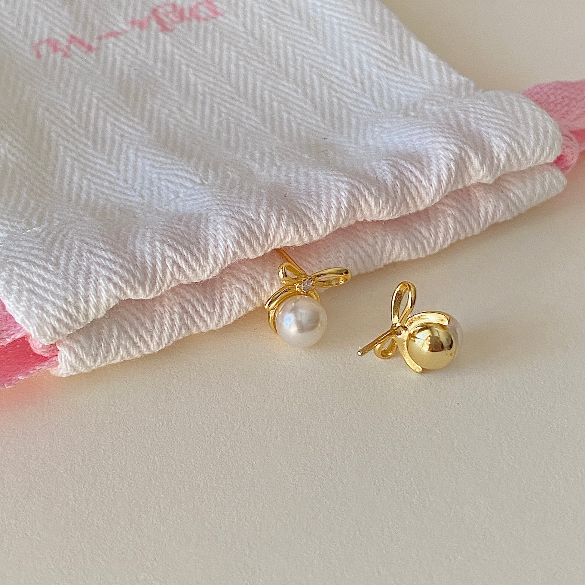 Gold bow ribbon pearl studs with tiny accent stone at knot, hypoallergenic posts
