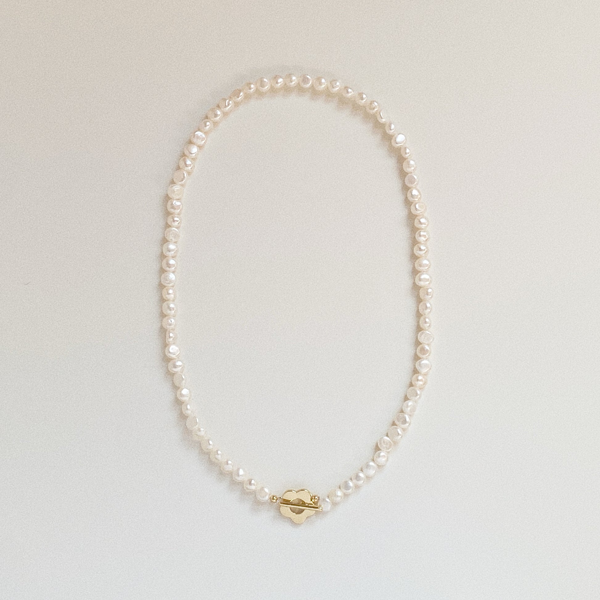 Full view of Bloom Toggle freshwater pearl necklace laid in a circle with flower clasp at the front