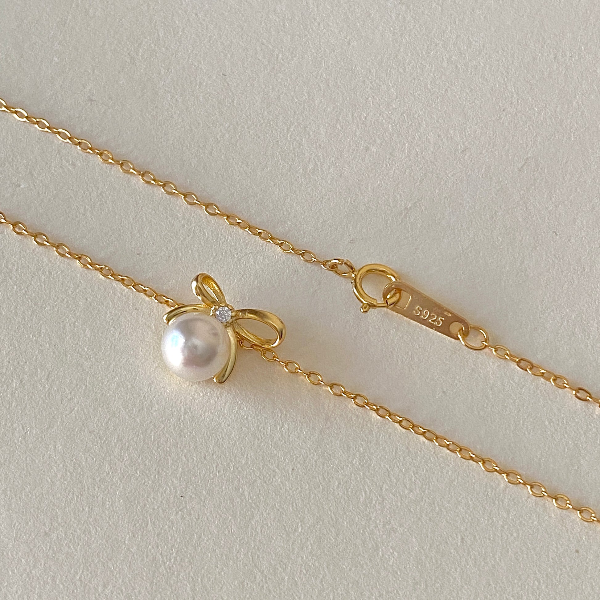 Gold bow pearl pendant necklace close-up, 6 mm pearl on 18k gold-plated 925 chain