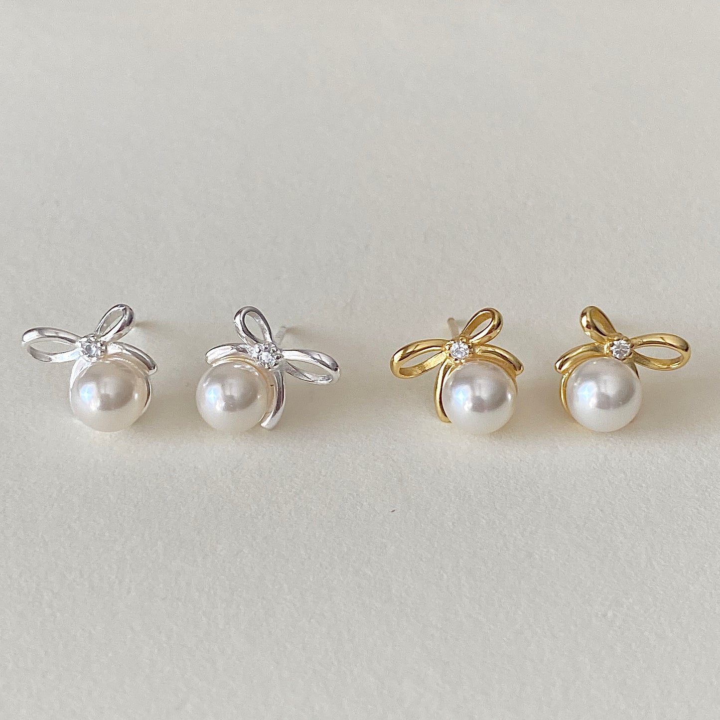 Bow pearl studs in gold and sterling silver side-by-side, small dainty pearl earrings