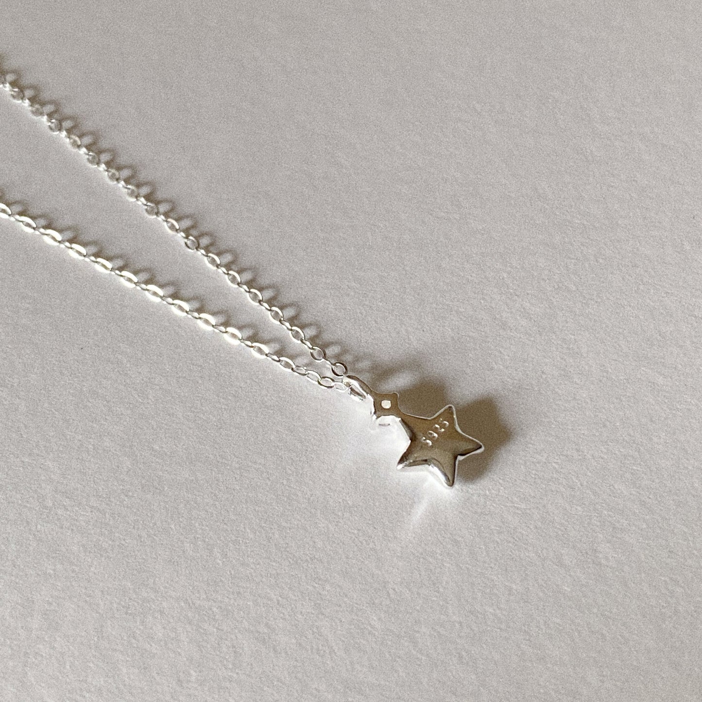 Close up of brushed sterling silver star pendant on delicate chain