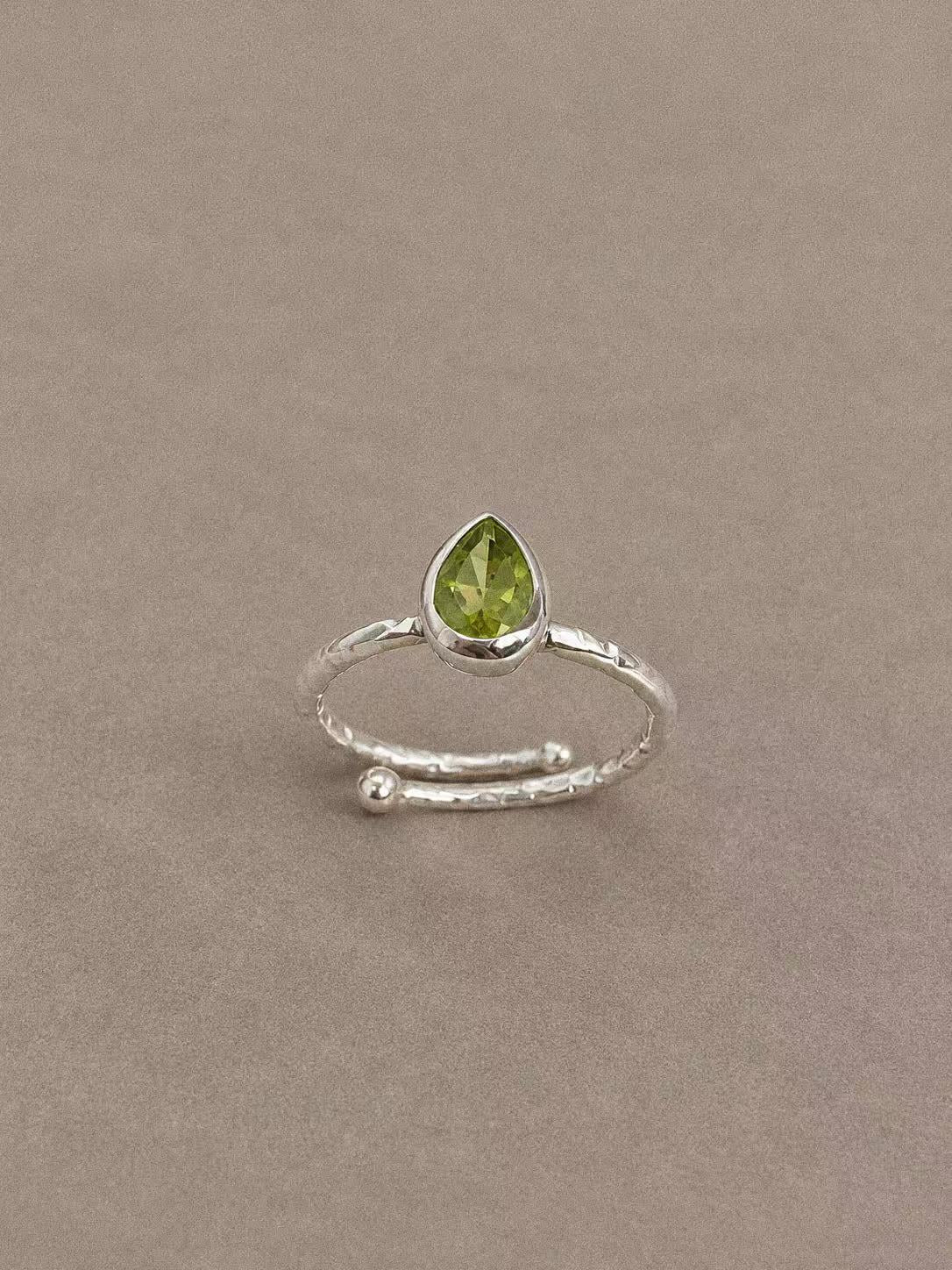 Peridot teardrop ring showing its faceted green stone and overlapping textured silver band ends