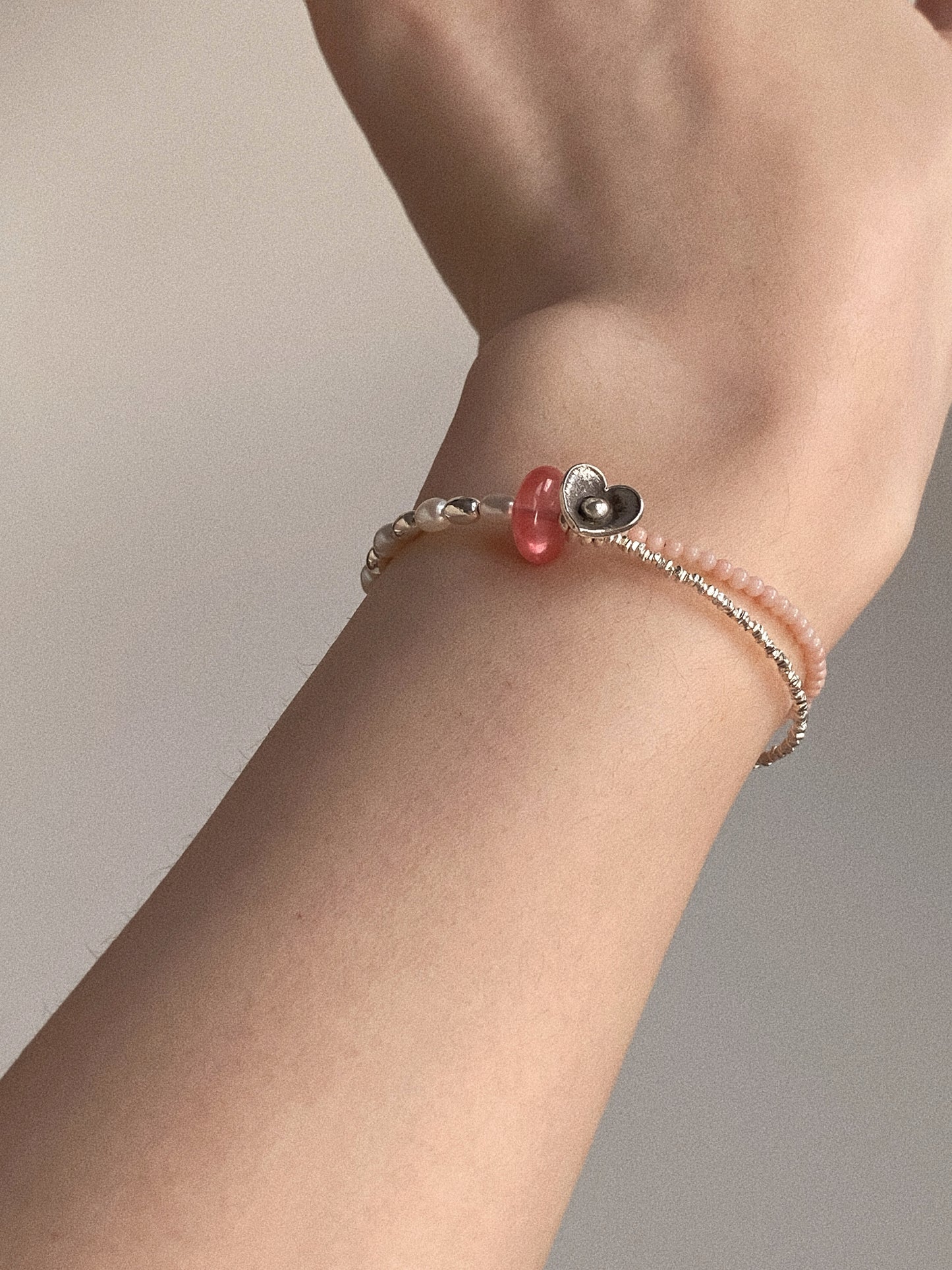 A woman wearing the cherry quartz and pink coral structured silver bracelet, highlighting its modern romantic style.