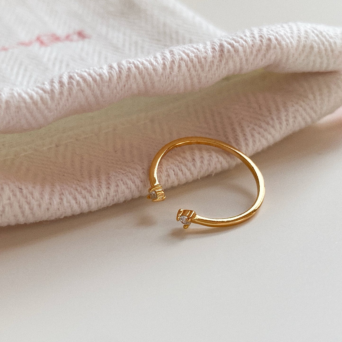 Close-up of adjustable gold pinky ring with two cubic zirconia ends