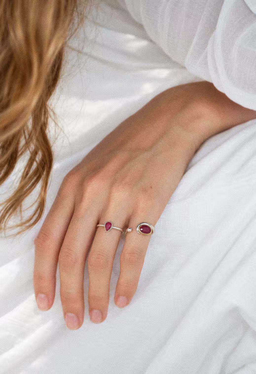 Ruby teardrop ring worn on a hand beside an oval ruby ring; jewellery styling image
