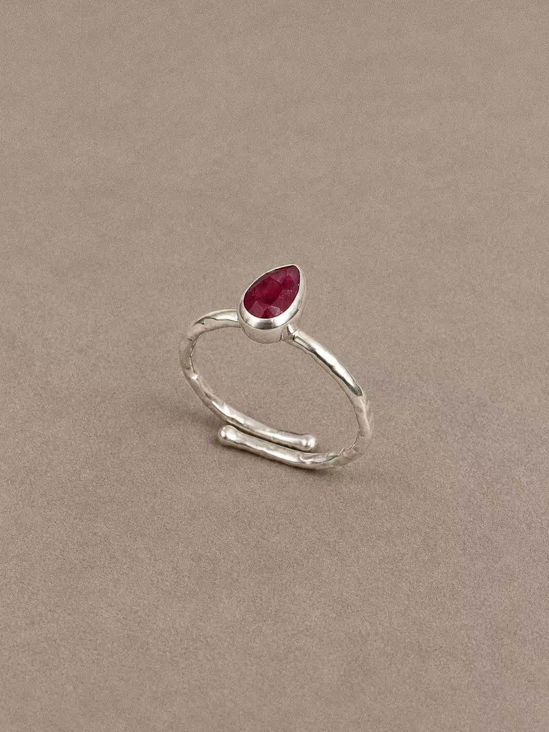 Angled view of the pear-shaped ruby ring showing its silver bezel and overlapping band ends