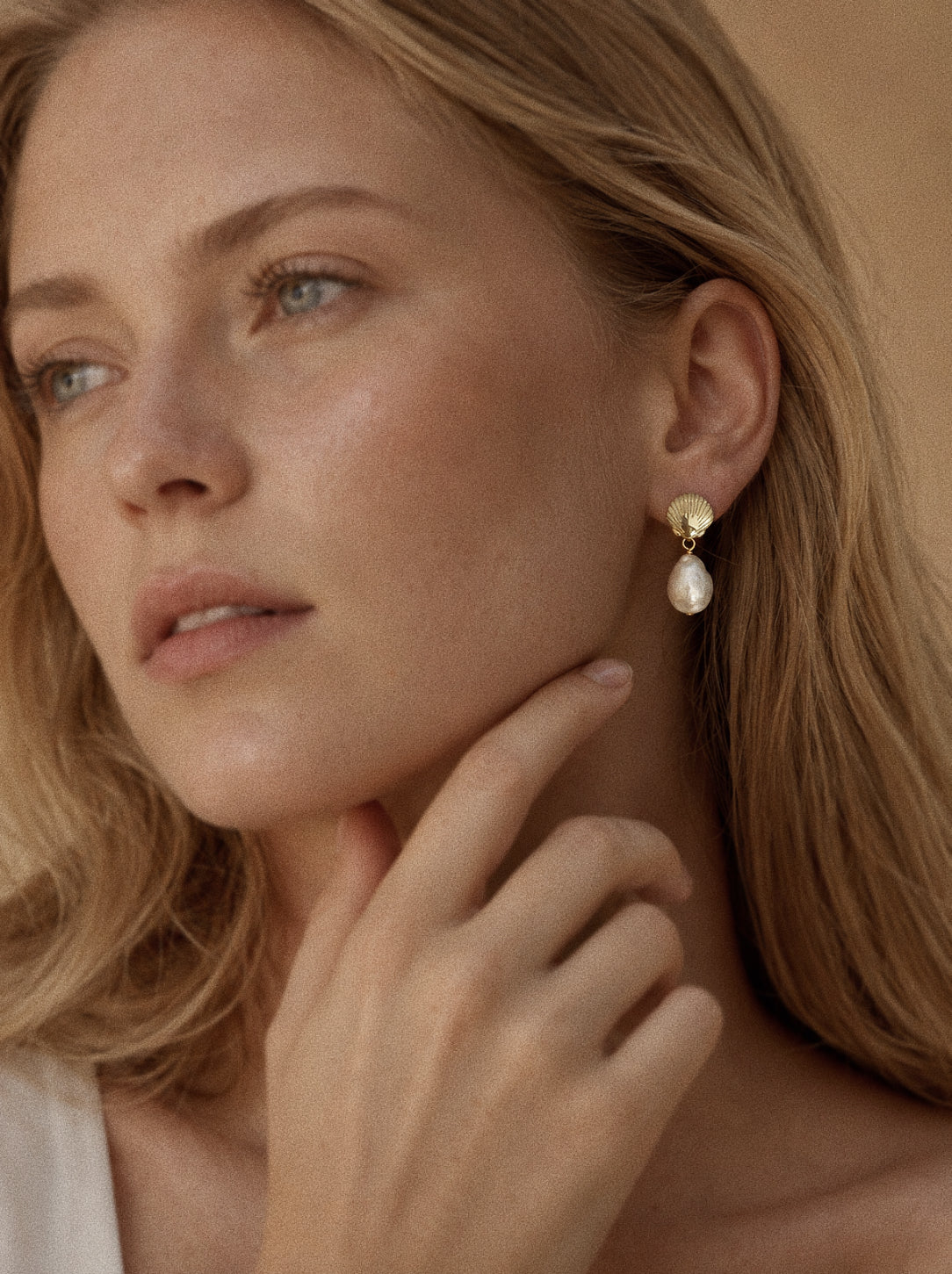 Shore gold shell and freshwater baroque pearl earrings worn on the ear, showing their approx. 26 mm drop.