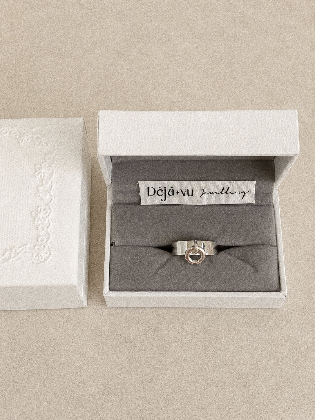 Orbit silver charm ring in a Deja Vu Jewellery gift box with a stitched fabric brand label.