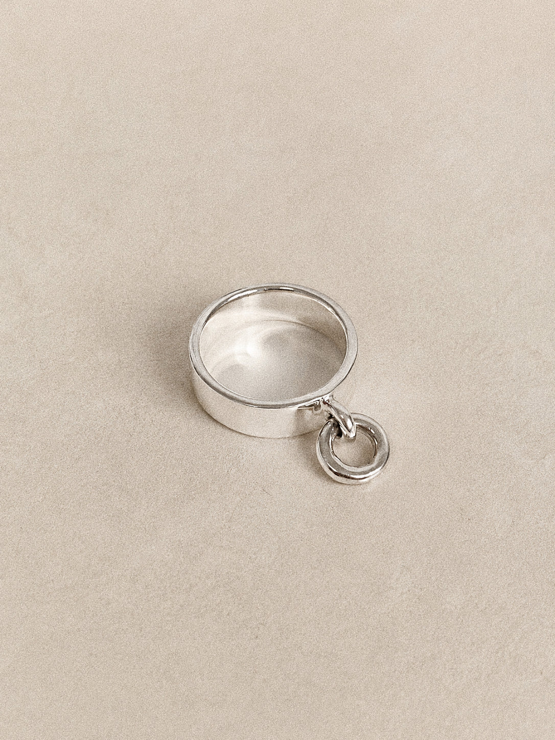 Top view of the wide band silver charm ring lying flat, its mirror polished 925 band carrying a small round hoop.