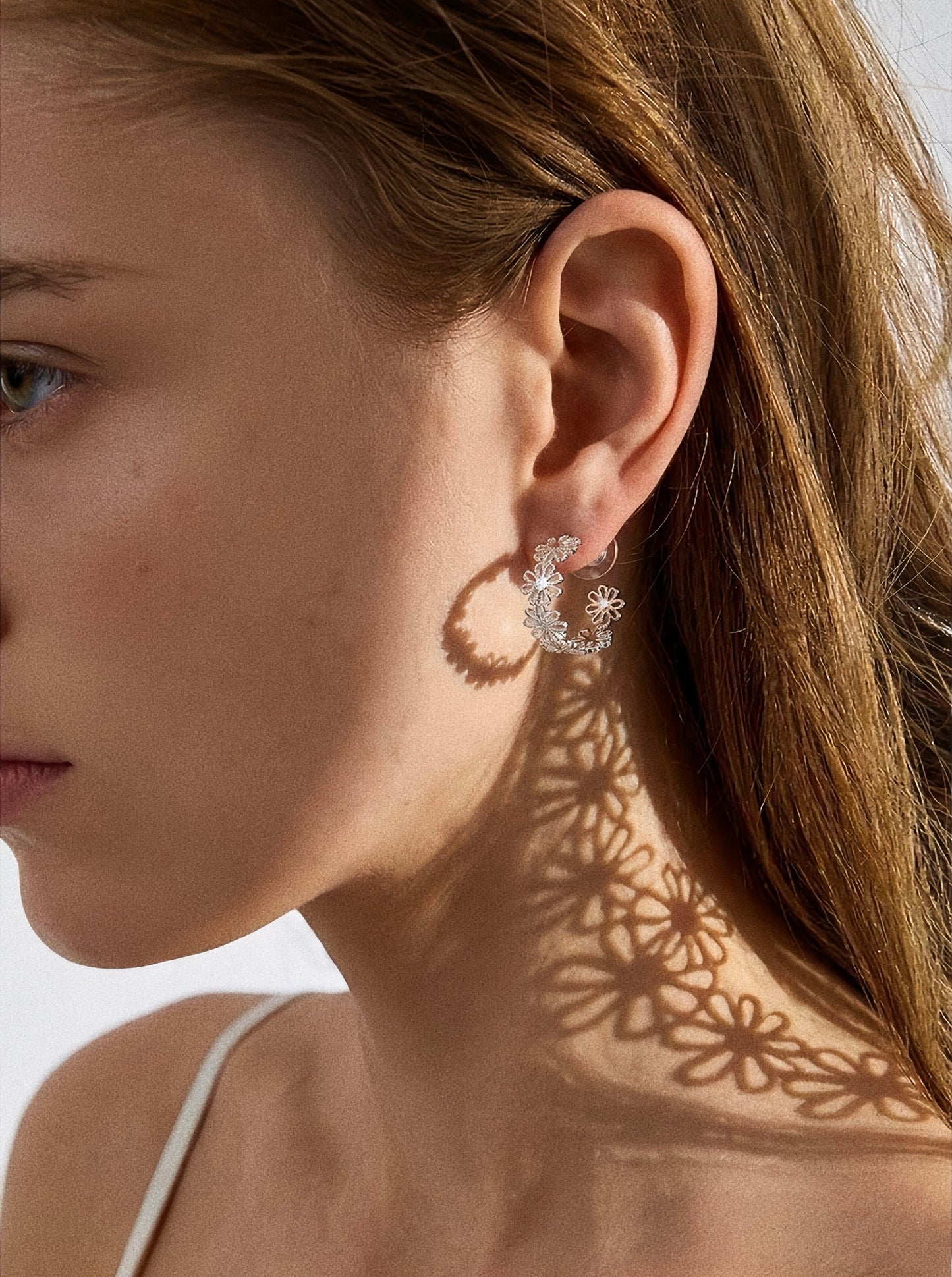 Silver daisy lace floral hoop earring worn on model showing 19mm hoop size and floral shadow on neck