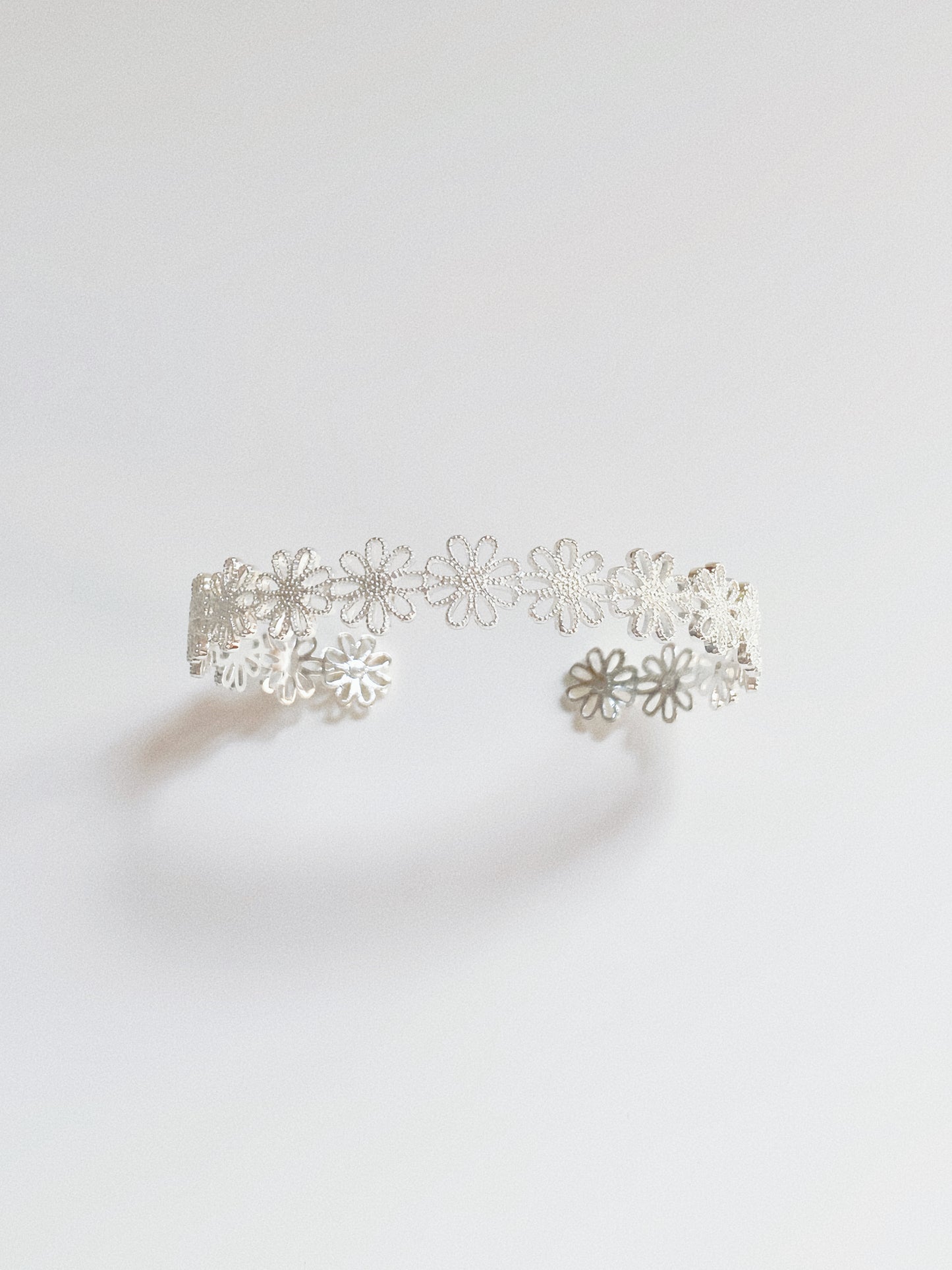 Silver daisy lace open cuff bracelet showing delicate floral lacework and open-band shape