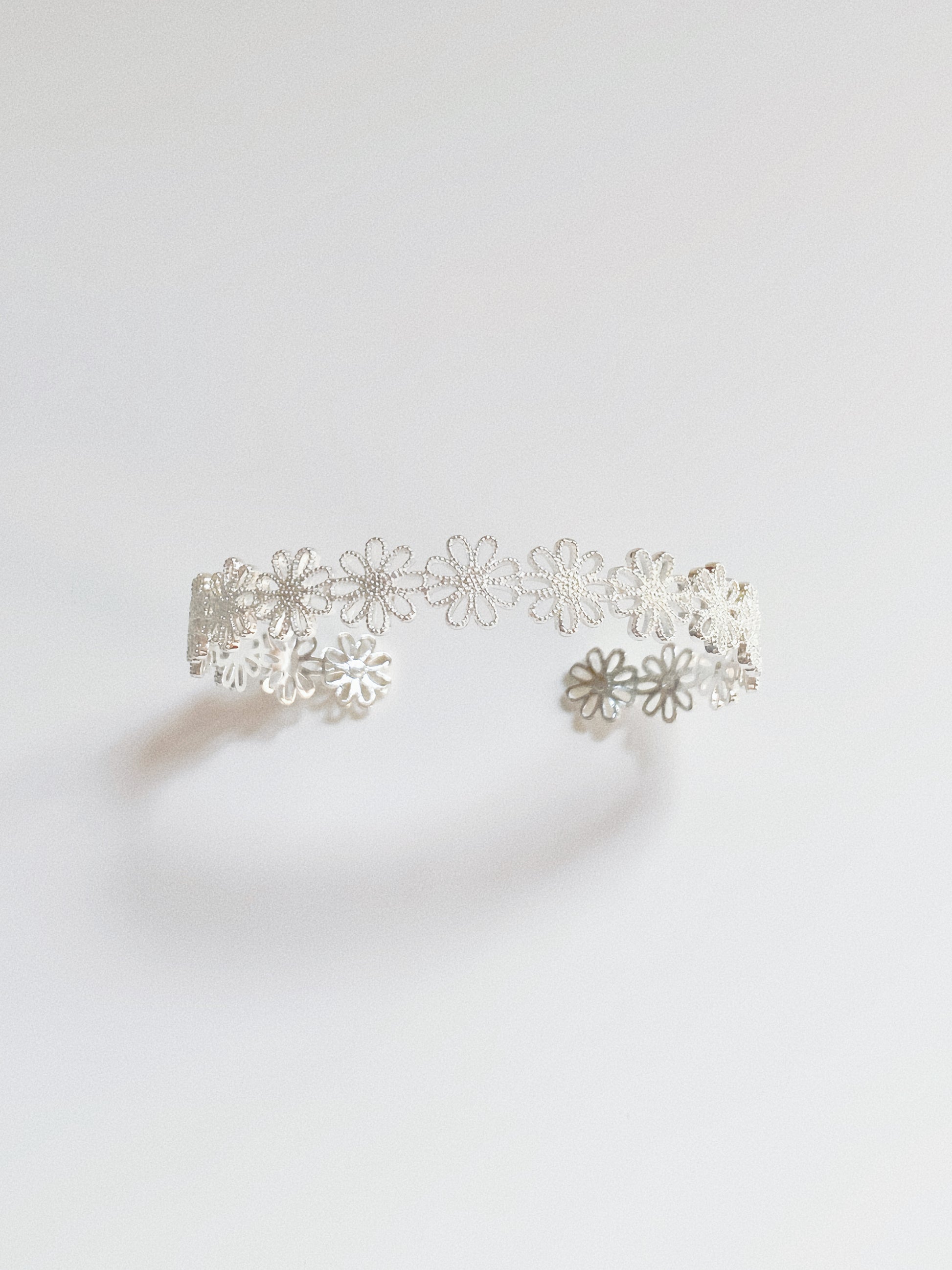 Silver daisy lace open cuff bracelet showing delicate floral lacework and open-band shape