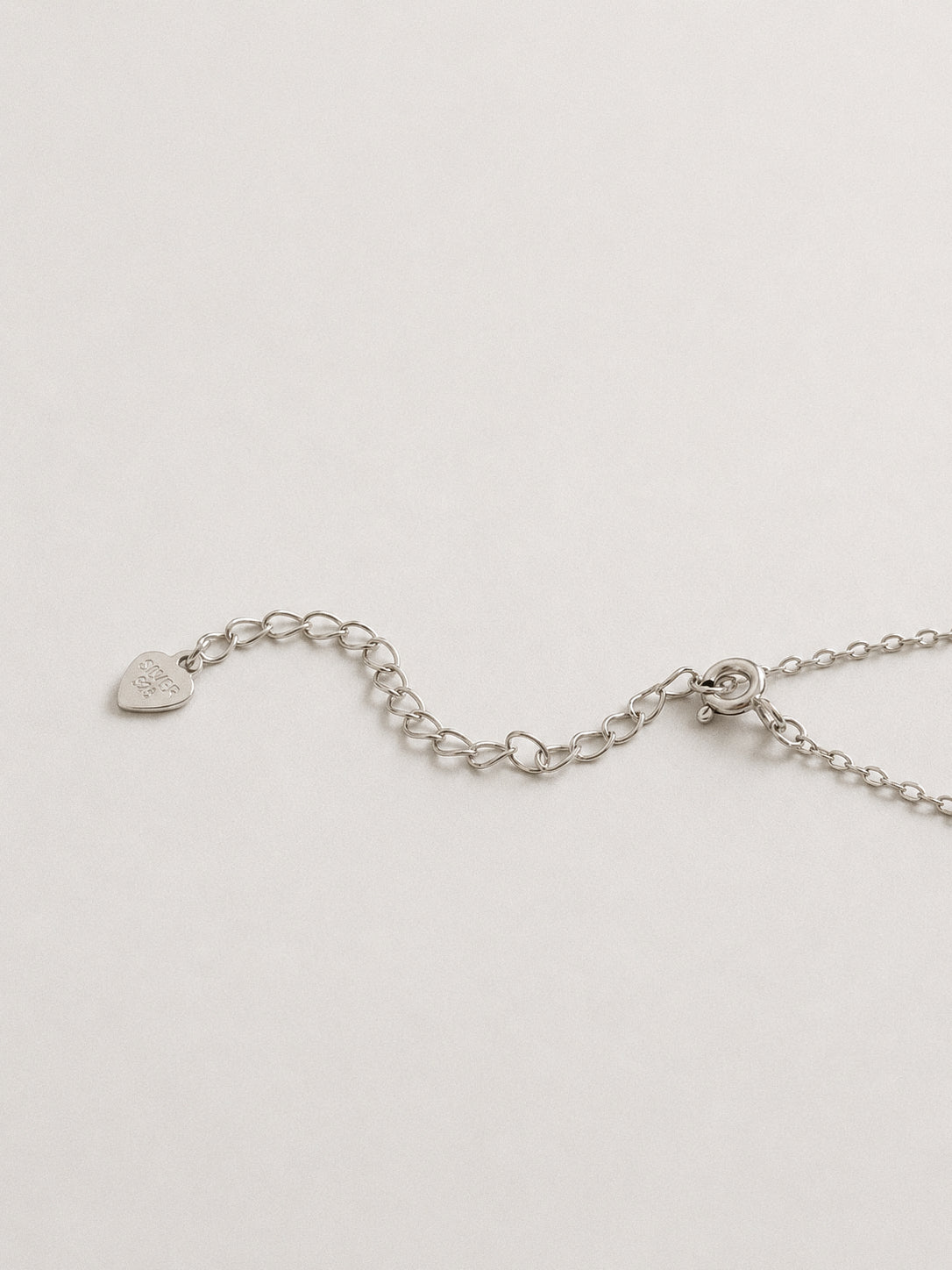 Spring ring clasp, extender chain and a small heart-shaped 925 silver tag on a sterling silver necklace