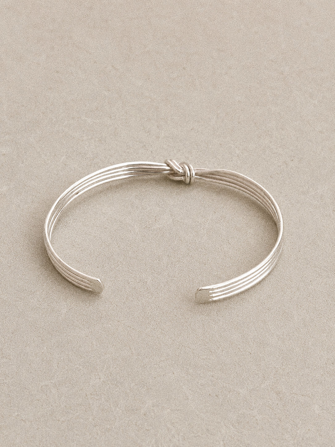 Full view of the hand tied silver knot bangle showing the open cuff design and parallel wire strands