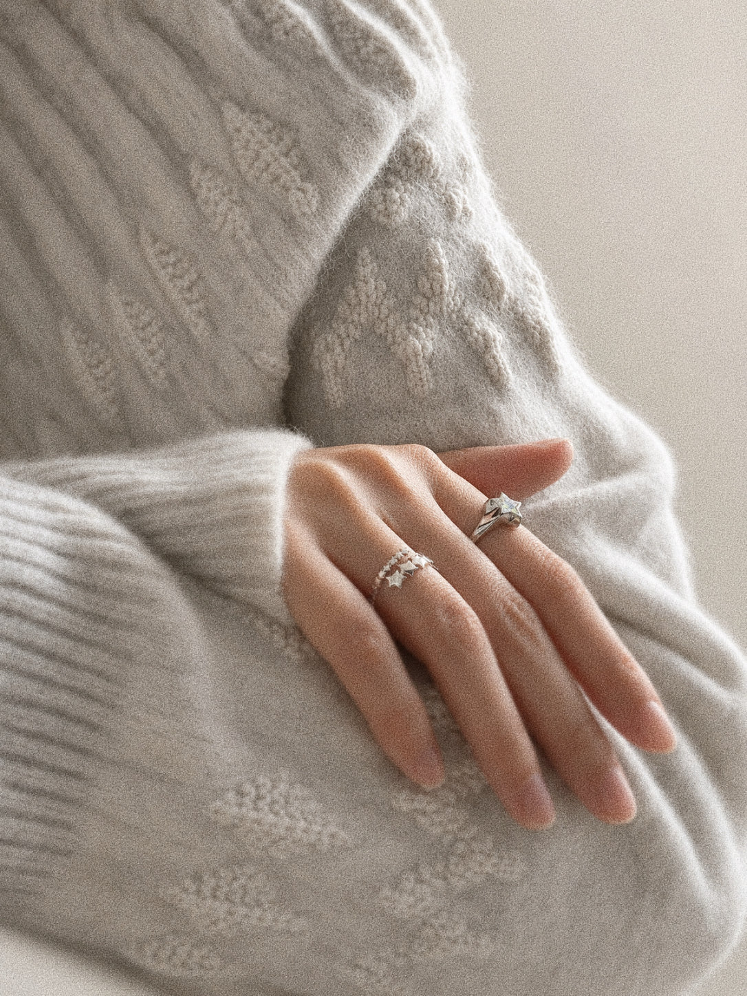 Drift multi star ring worn on the hand and layered with a larger polished silver star ring.
