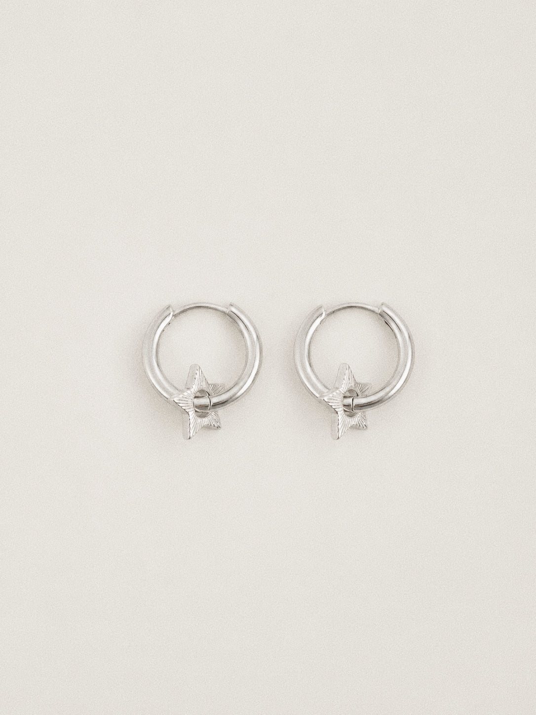 Top view of the silver star huggie hoops showing the neat hoop shape and the star charm resting inside.