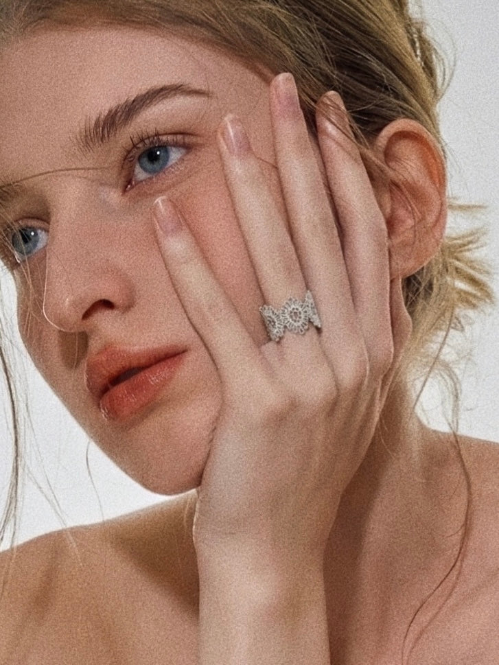 Vintage lace silver statement ring worn on hand resting against face in editorial portrait styling
