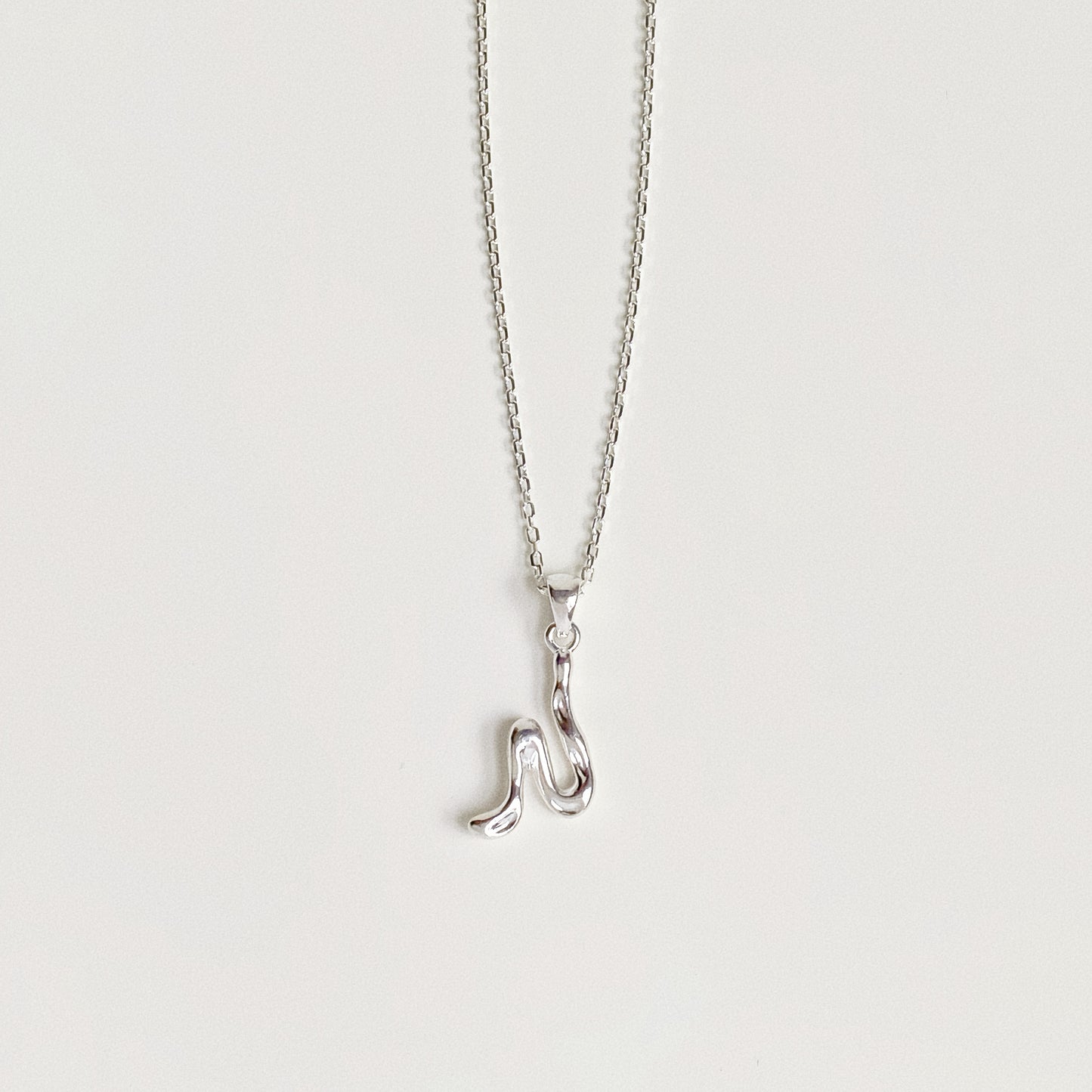 Sterling silver alphabet necklace featuring abstract molten letter pendant on white background.