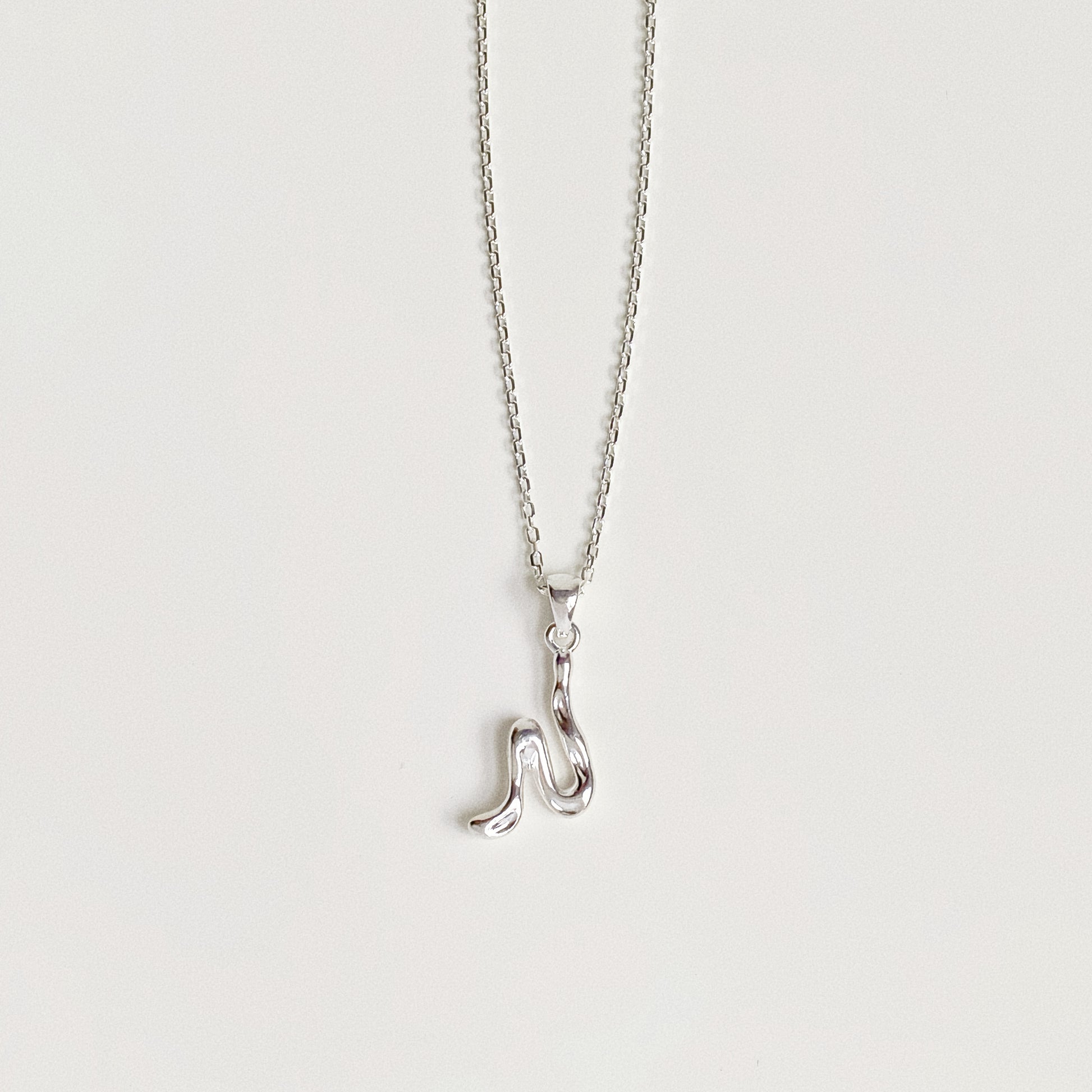 Sterling silver alphabet necklace featuring abstract molten letter pendant on white background.